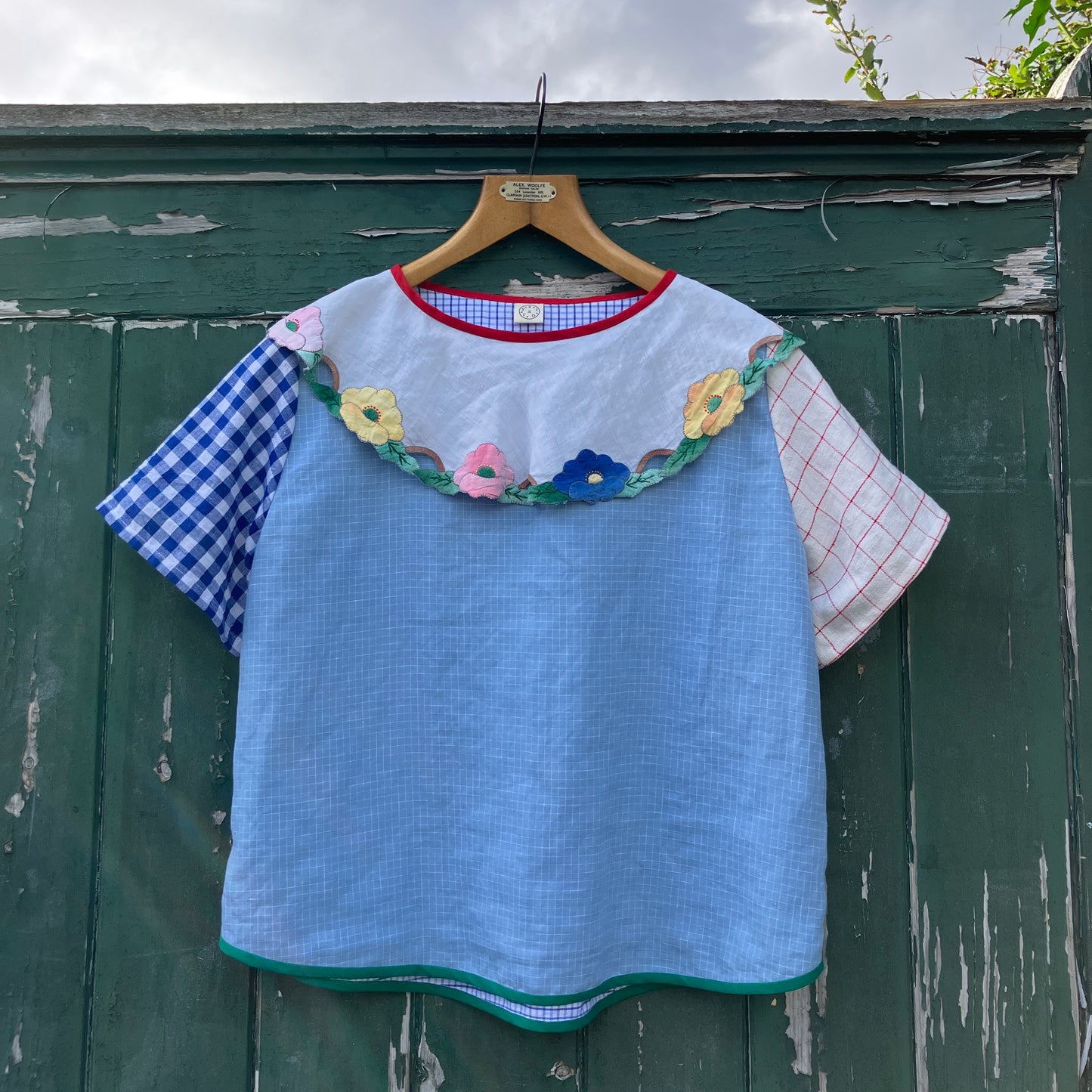 Short-sleeved top made from found offcuts of checked linen and a round floral table mat forming the collar.