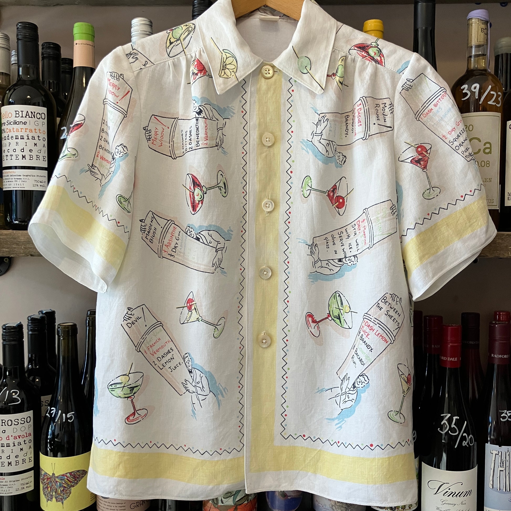 Shirt with cocktail-themed design in front of wine bottles