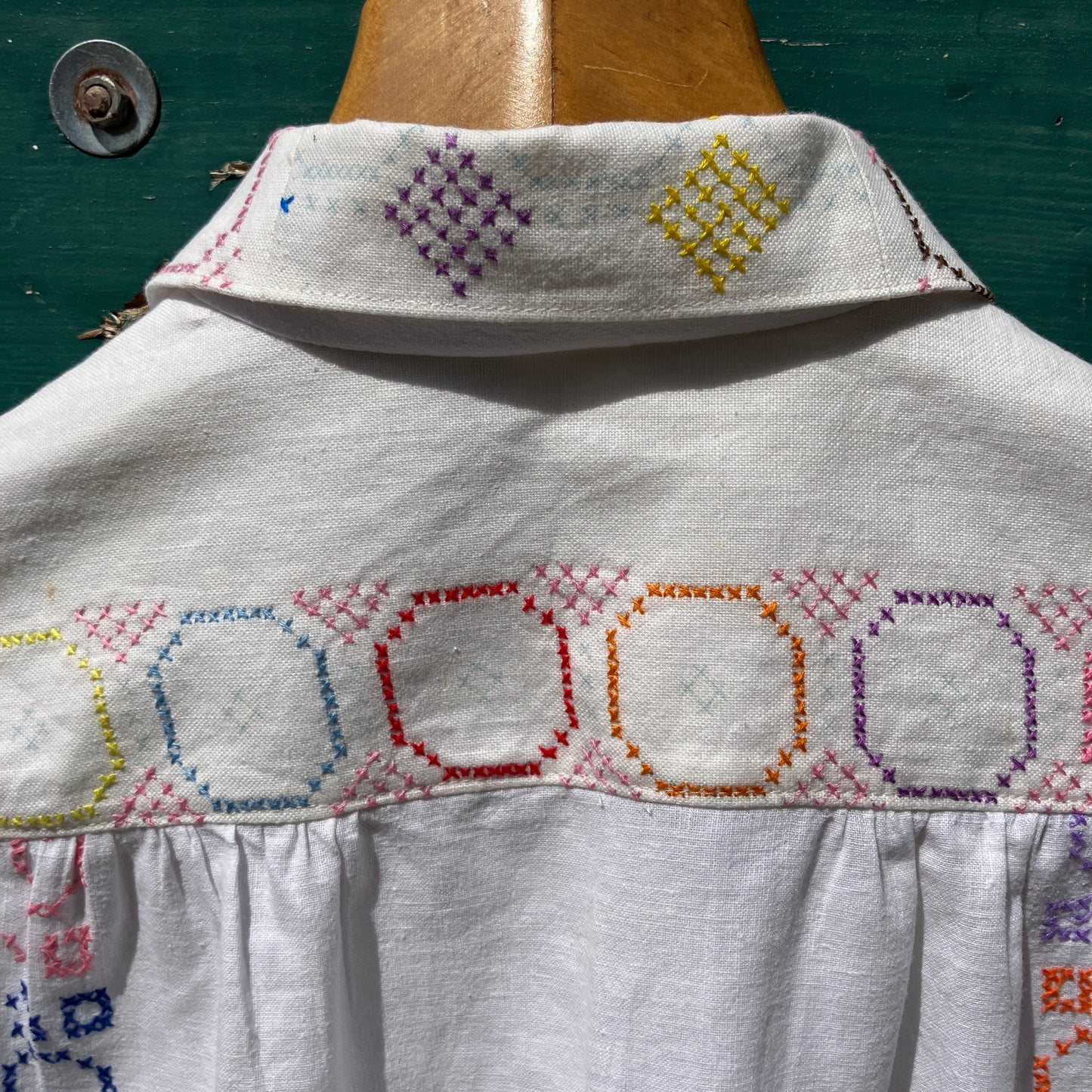 Shirt made from a selection of recycled vintage cotton tablecloths with floral and geometric cross stitch patterns