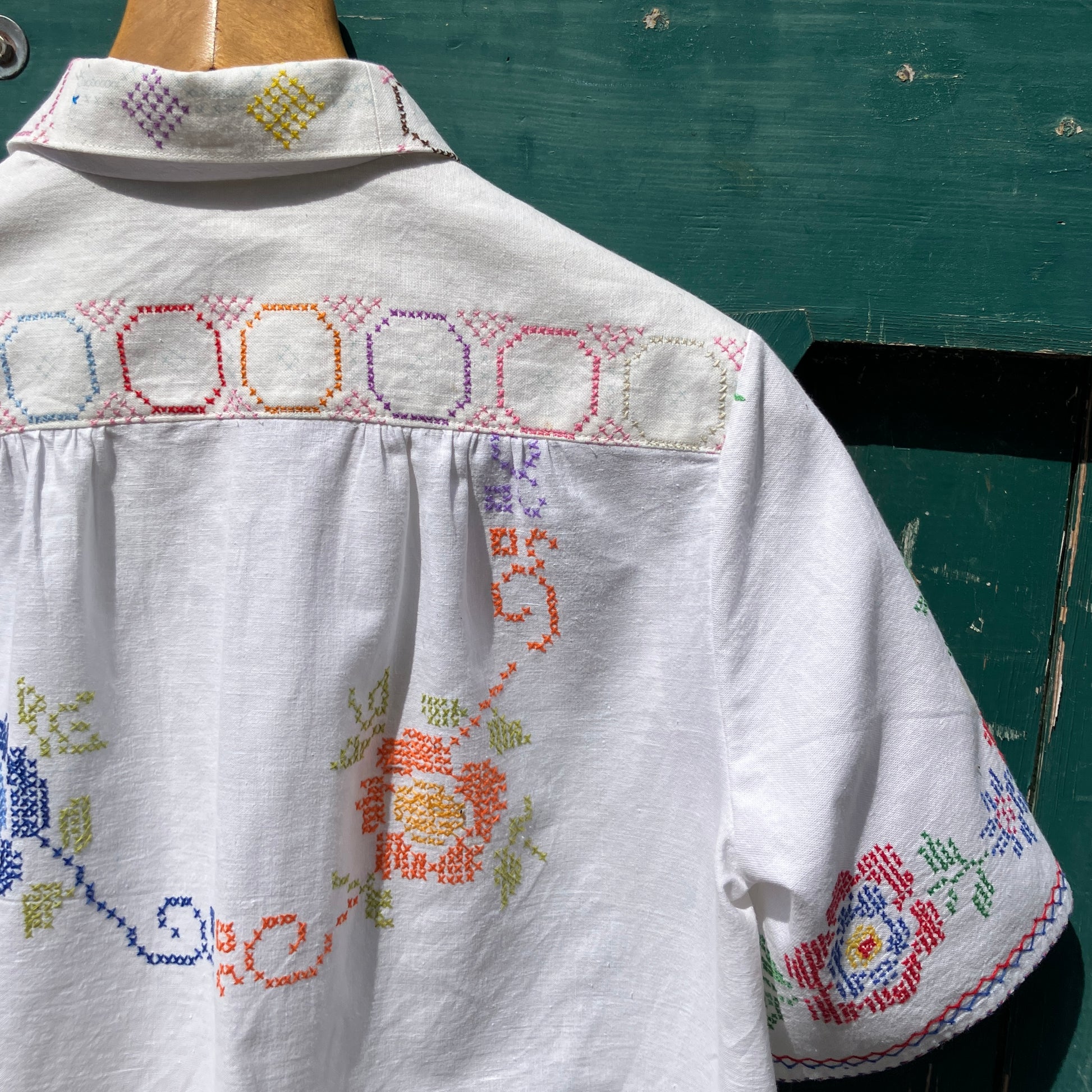 Shirt made from a selection of recycled vintage cotton tablecloths with floral and geometric cross stitch patterns