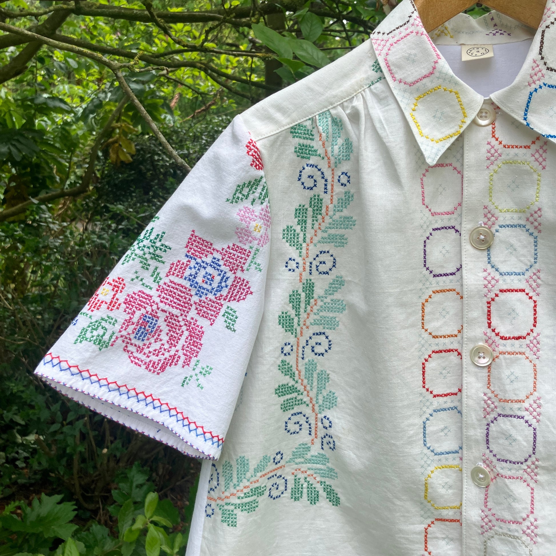 Shirt made from a selection of recycled vintage cotton tablecloths with floral and geometric cross stitch patterns