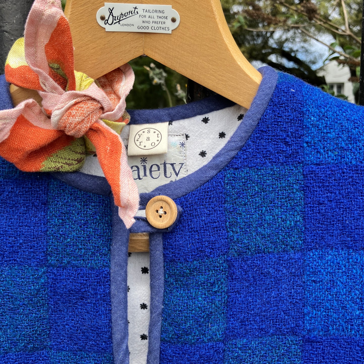 Vest/gilet/waistcoat made from a reclaimed blue checkerboard weave Irish wool Gaiety blanket, photographed in front of a lilac bush