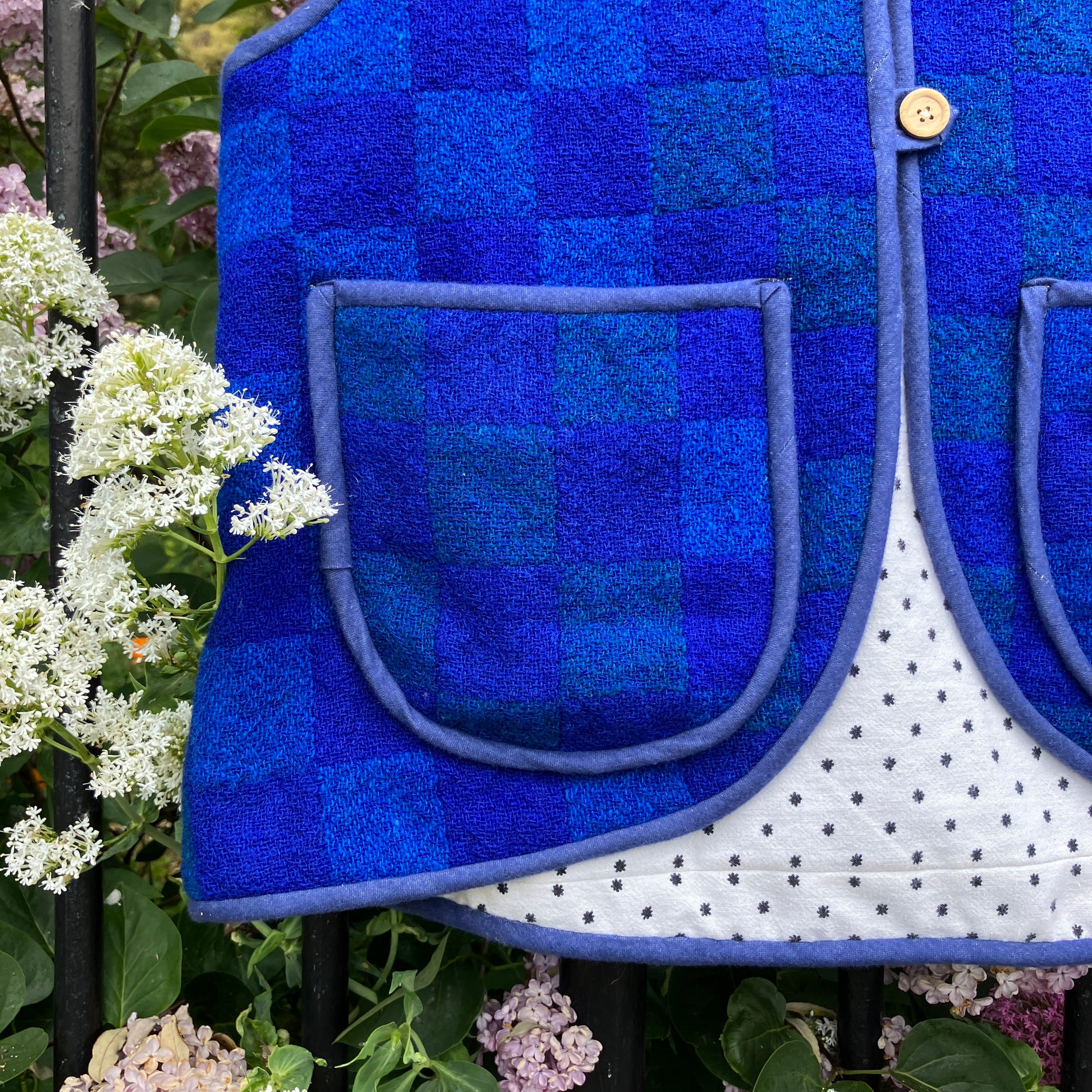 Vest/gilet/waistcoat made from a reclaimed blue checkerboard weave Irish wool Gaiety blanket, photographed in front of a lilac bush (close-up of pocket)
