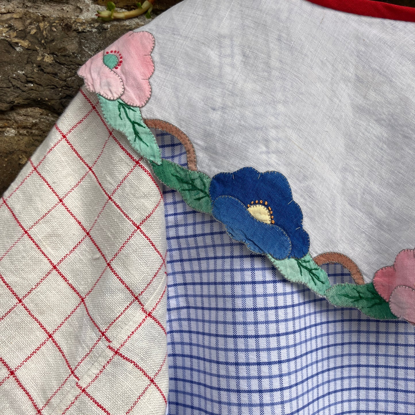 Short-sleeved top made from found offcuts of checked linen and a round floral table mat forming the collar.