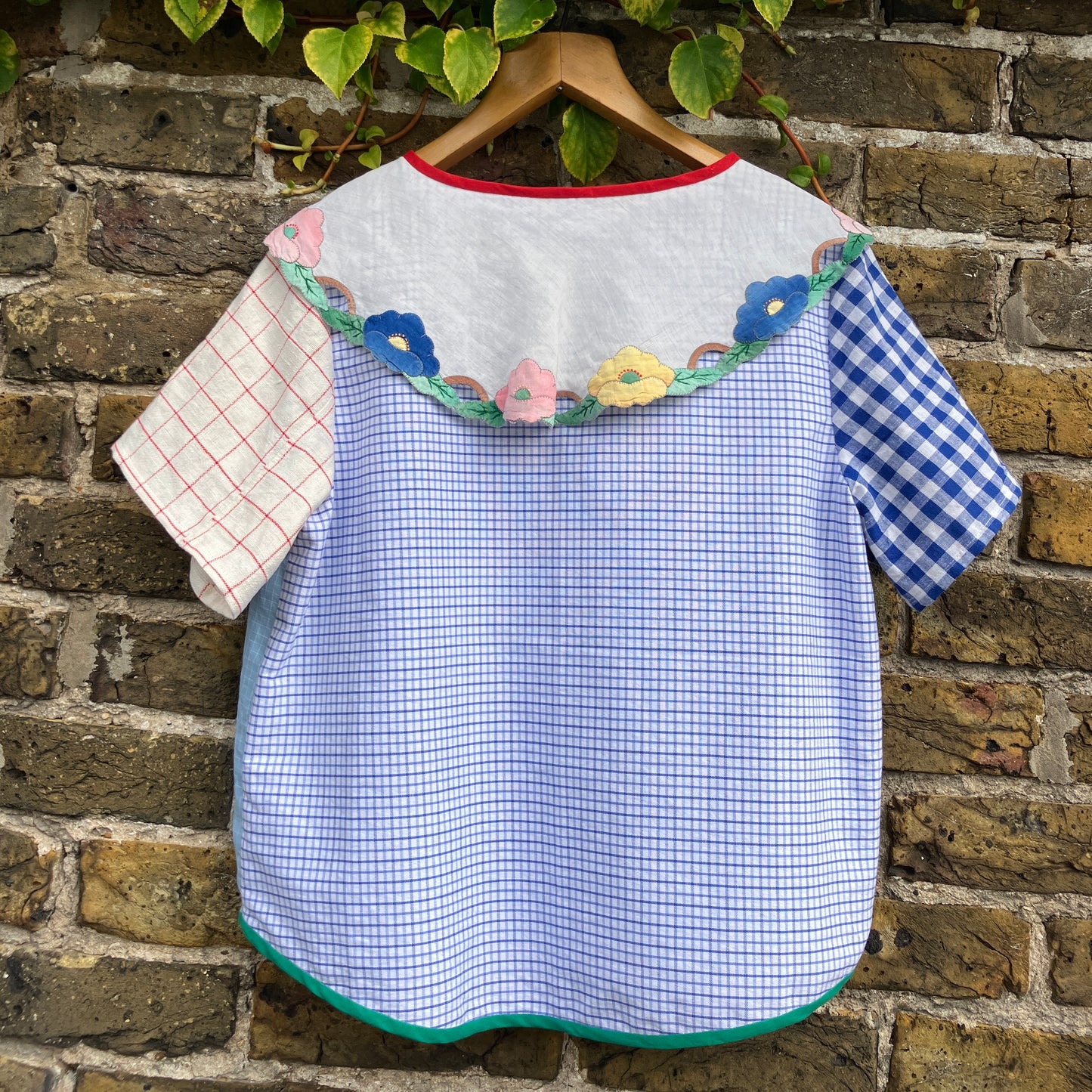 Short-sleeved top made from found offcuts of checked linen and a round floral table mat forming the collar.