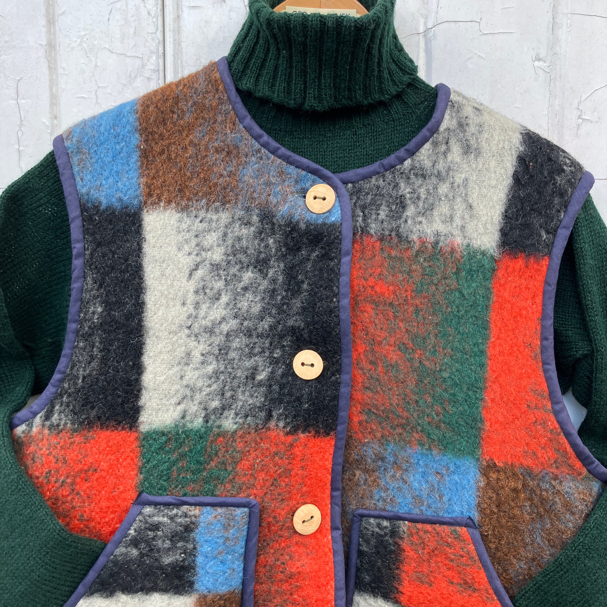 cosy vest or waistcoat made from a thick vintage wool blanket in rich hues of green, orange, blue and brown reminiscent of an oil painting