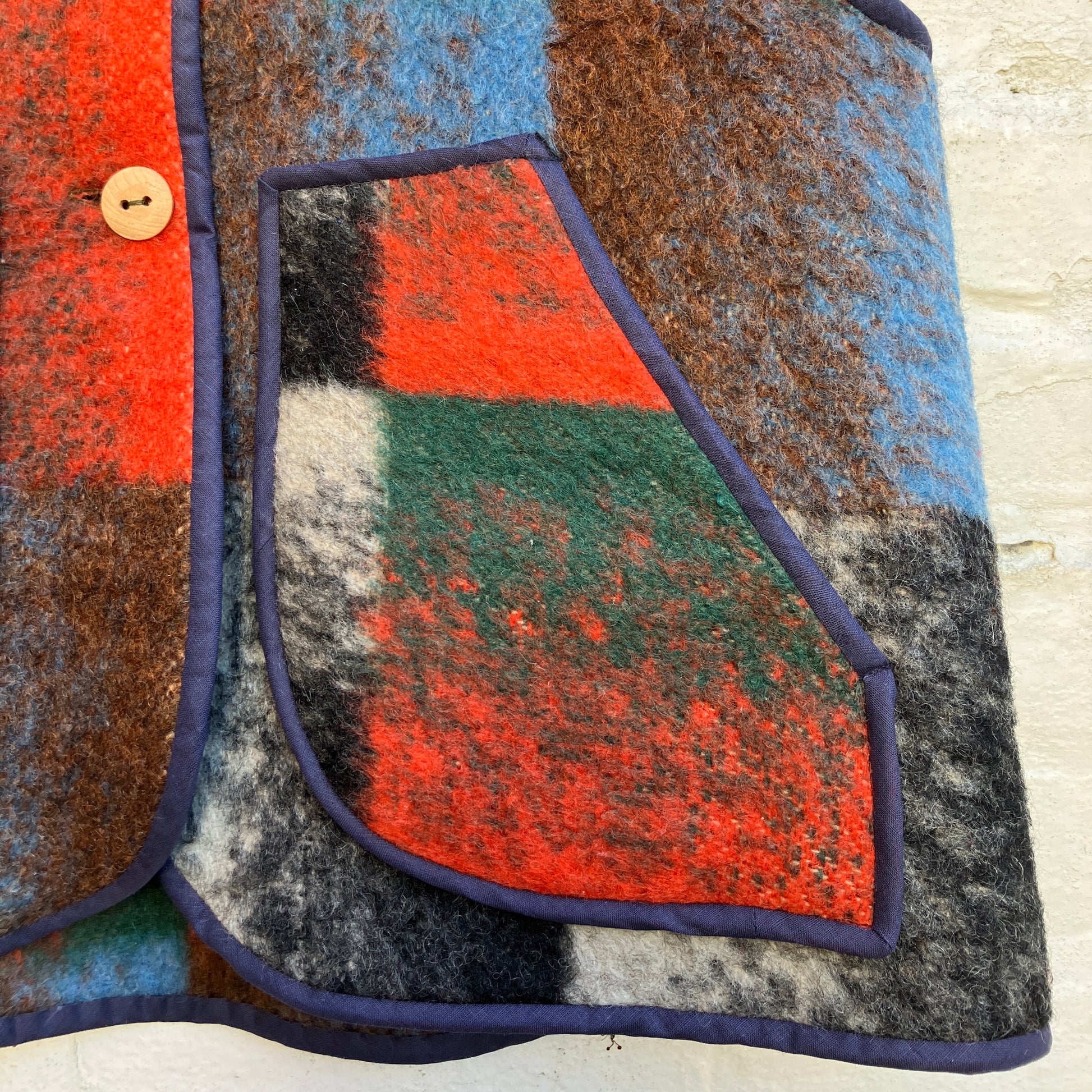 cosy vest or waistcoat made from a thick vintage wool blanket in rich hues of green, orange, blue and brown reminiscent of an oil painting