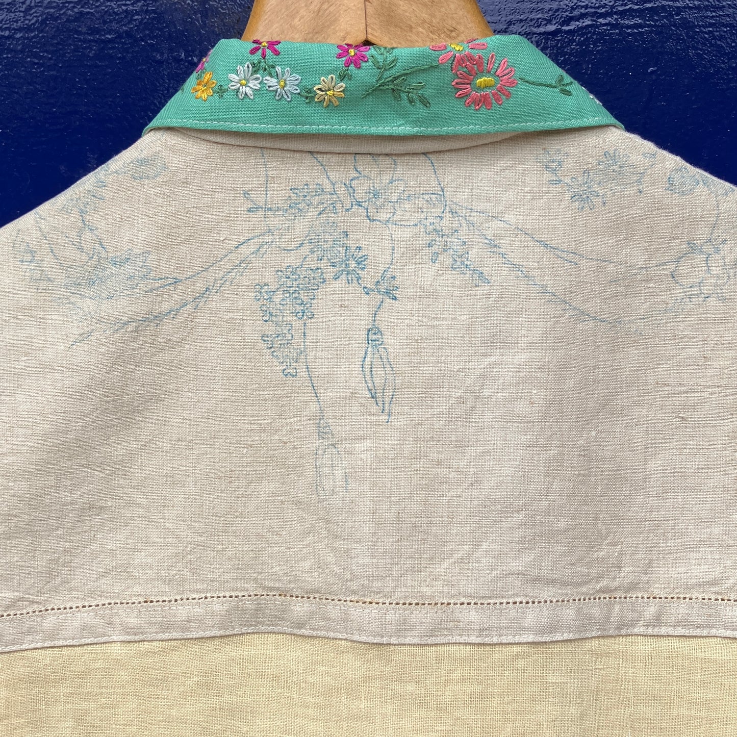 A short-sleeve button-front shirt made from reclaimed vintage tablecloths in neutrals with pink sleeves, and a light green collar.