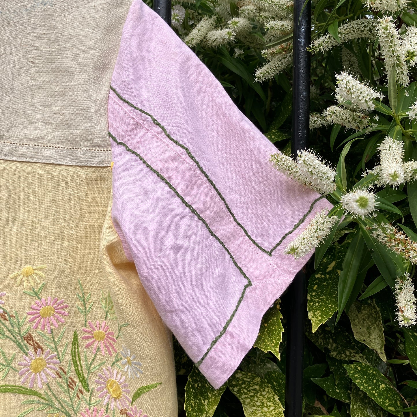 A short-sleeve button-front shirt made from reclaimed vintage tablecloths in neutrals with pink sleeves, and a light green collar.