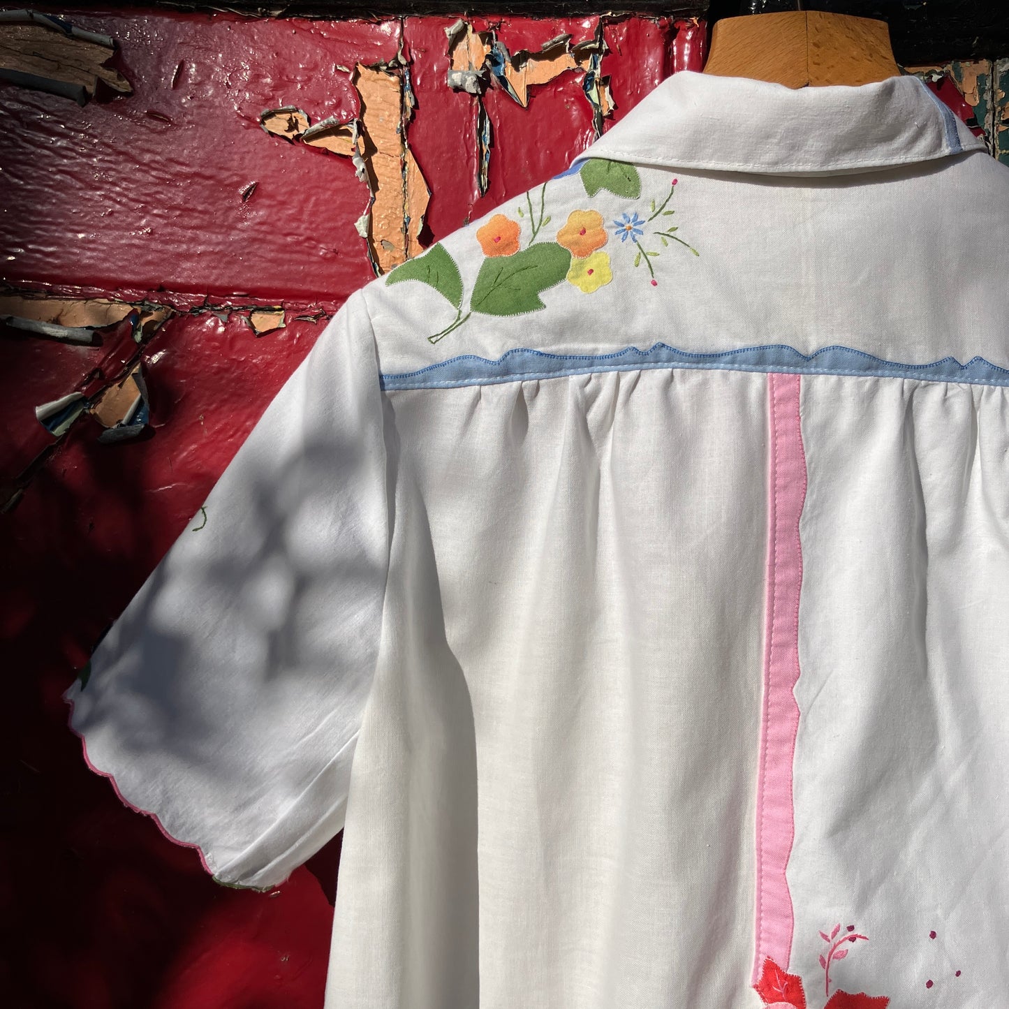 linen and cotton shirt made from a patchwork of reclaimed vintage napkins and placemats with detailed appliqué flowers and pastel borders