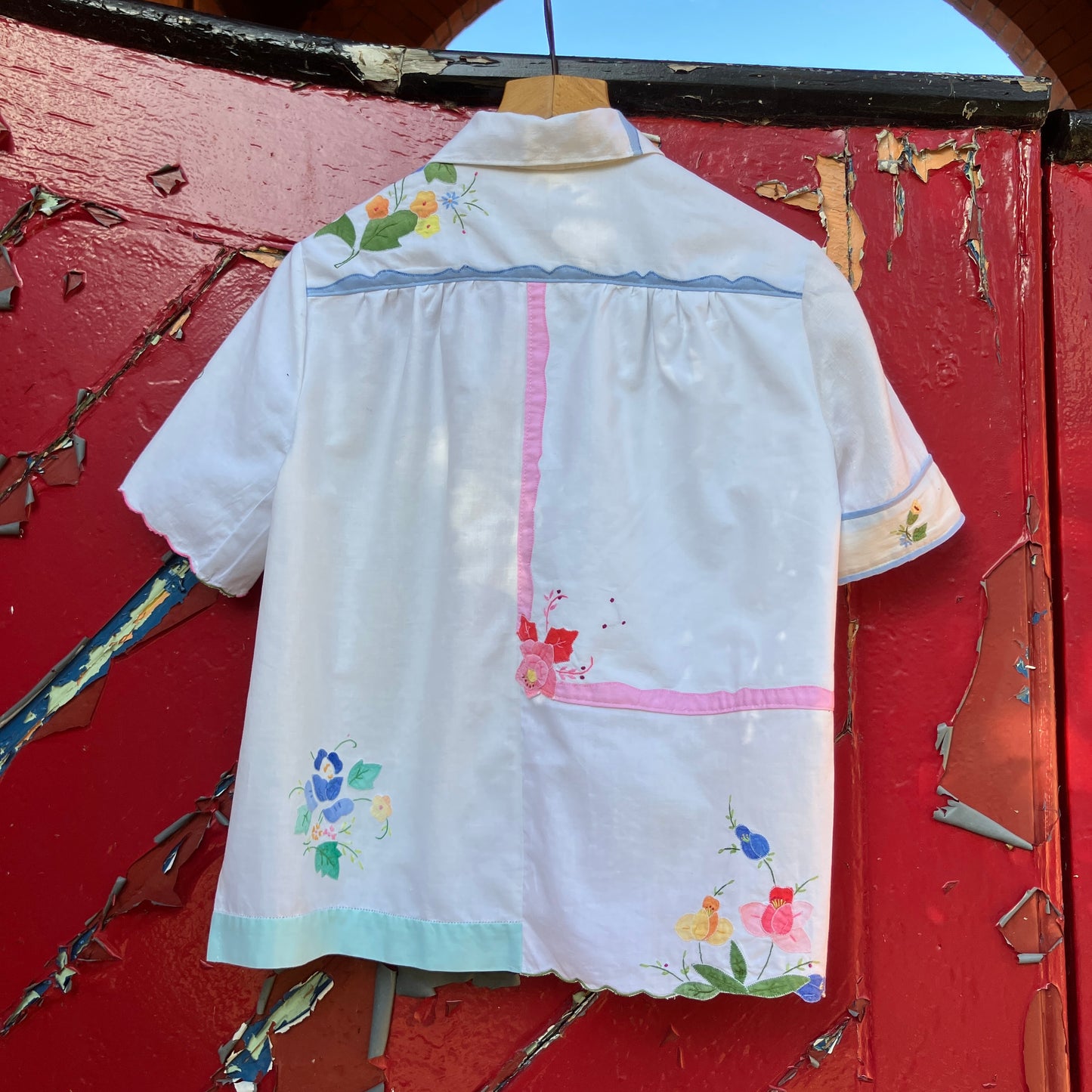 linen and cotton shirt made from a patchwork of reclaimed vintage napkins and placemats with detailed appliqué flowers and pastel borders