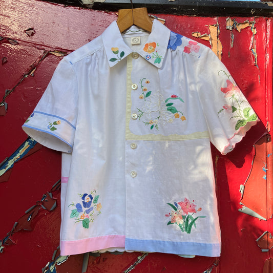 linen and cotton shirt made from a patchwork of reclaimed vintage napkins and placemats with detailed appliqué flowers and pastel borders