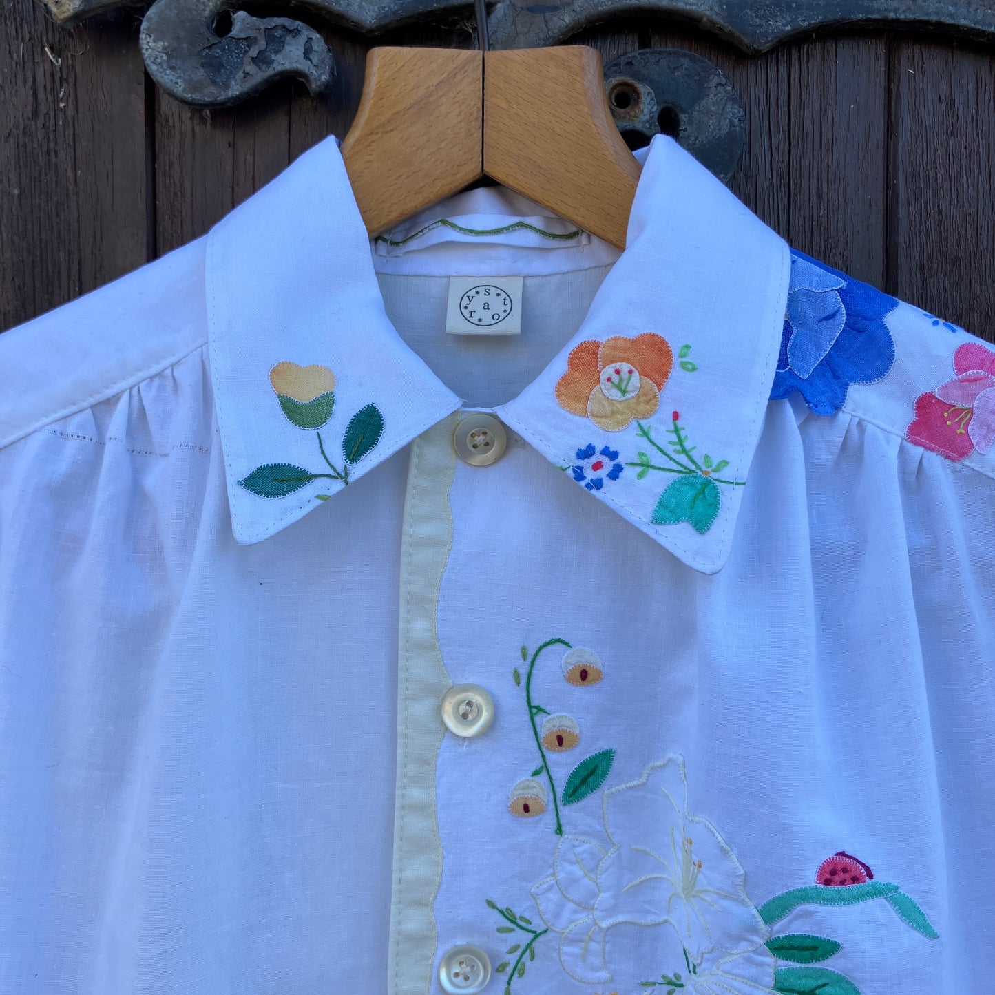 linen and cotton shirt made from a patchwork of reclaimed vintage napkins and placemats with detailed appliqué flowers and pastel borders