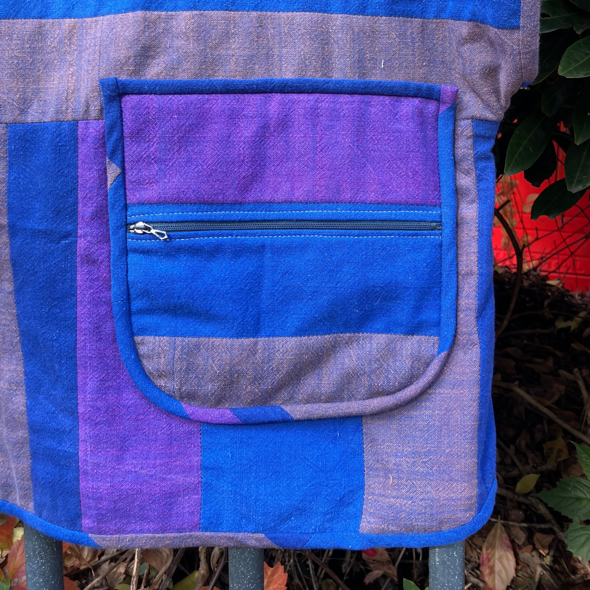 Blue and purple striped quilted top made from recycled fabrics, with a zip-up pocket