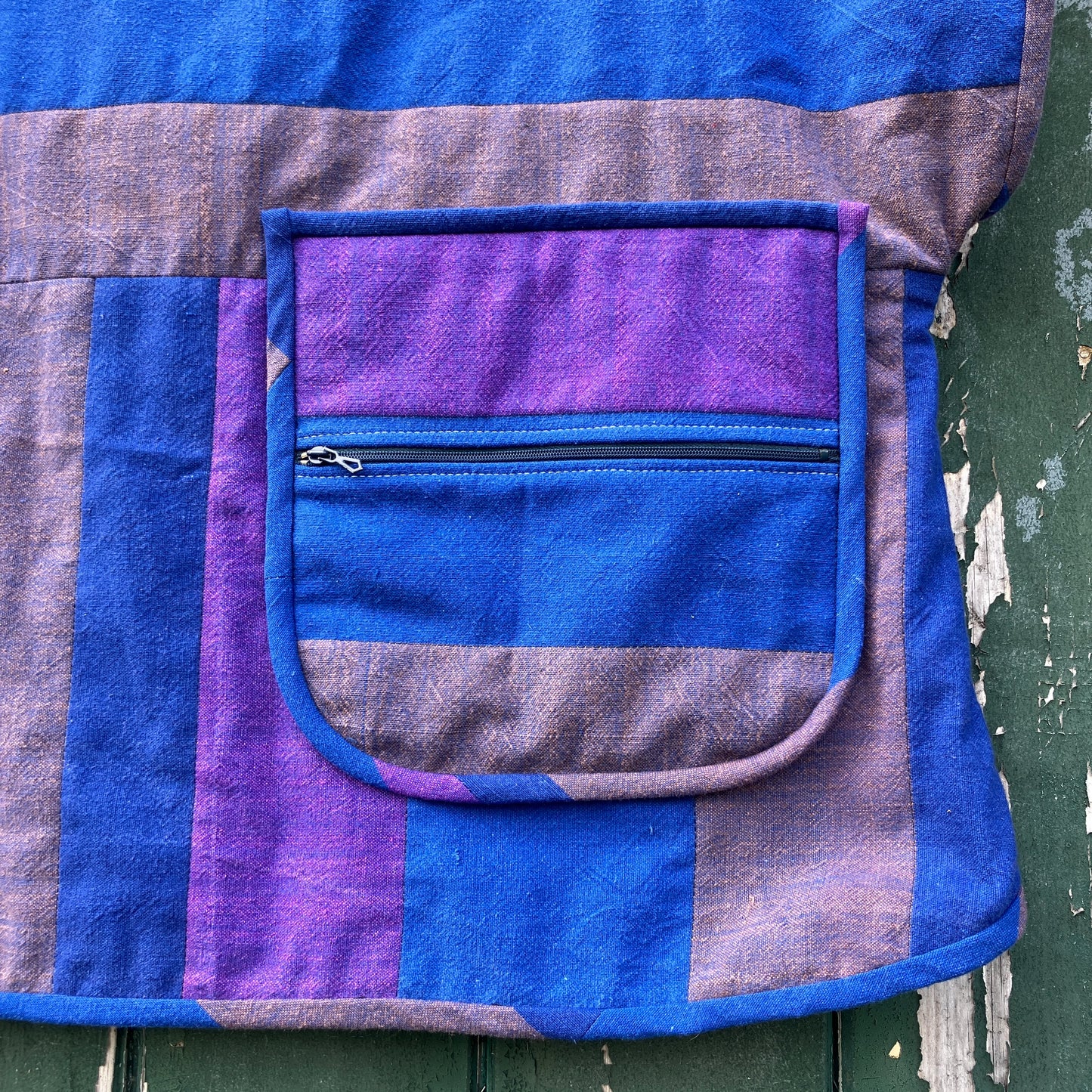 Blue and purple striped quilted top made from recycled fabrics, with a zip-up pocket