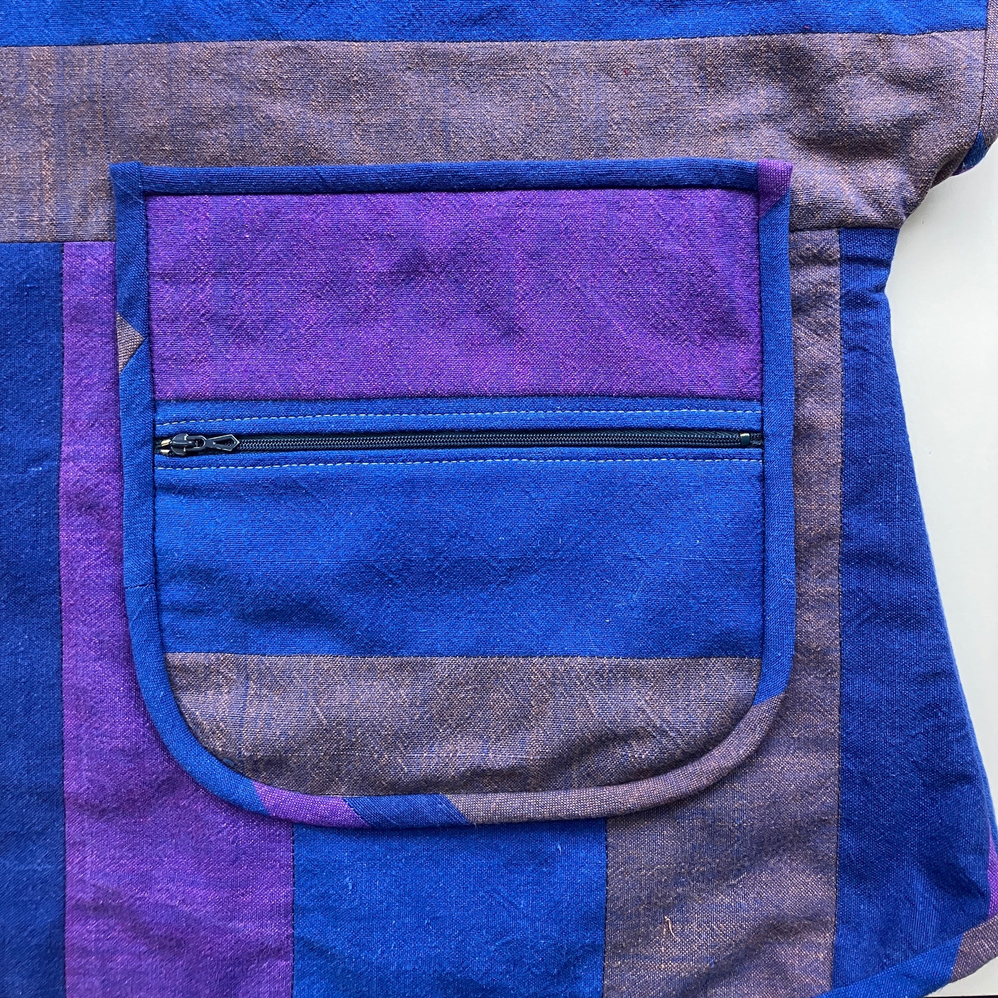 Blue and purple striped quilted top made from recycled fabrics, with a zip-up pocket