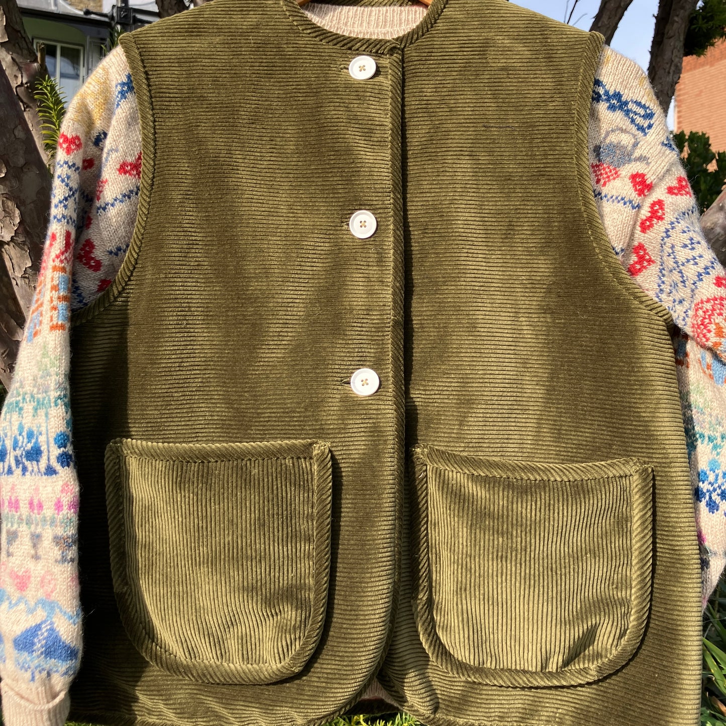 Reclaimed olive green corduroy vest with the wales going in a horizontal direction. Lined with dusky pink (possibly avocado dyed) cotton