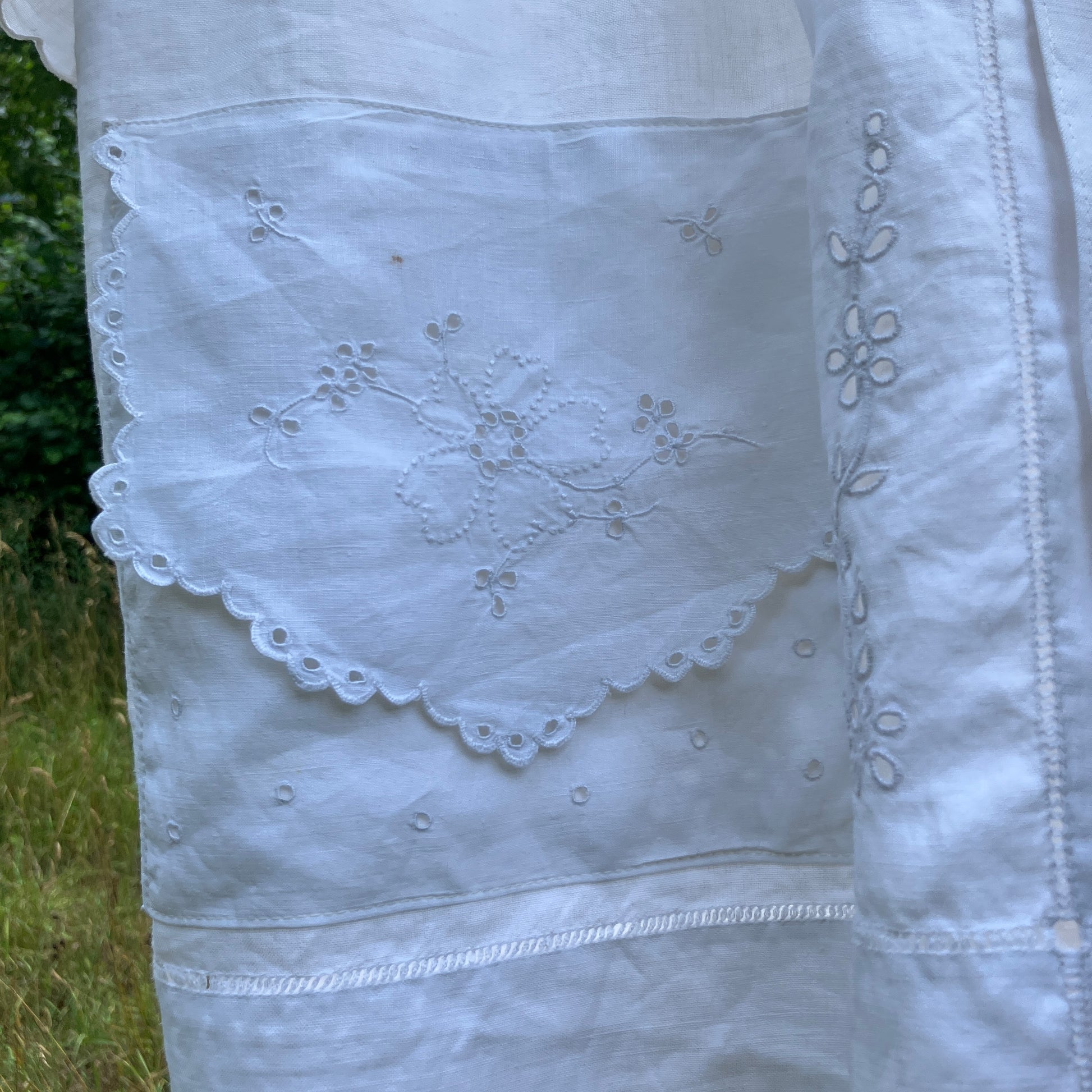 Blouse made from recycled table linen on a hanger against a natural background