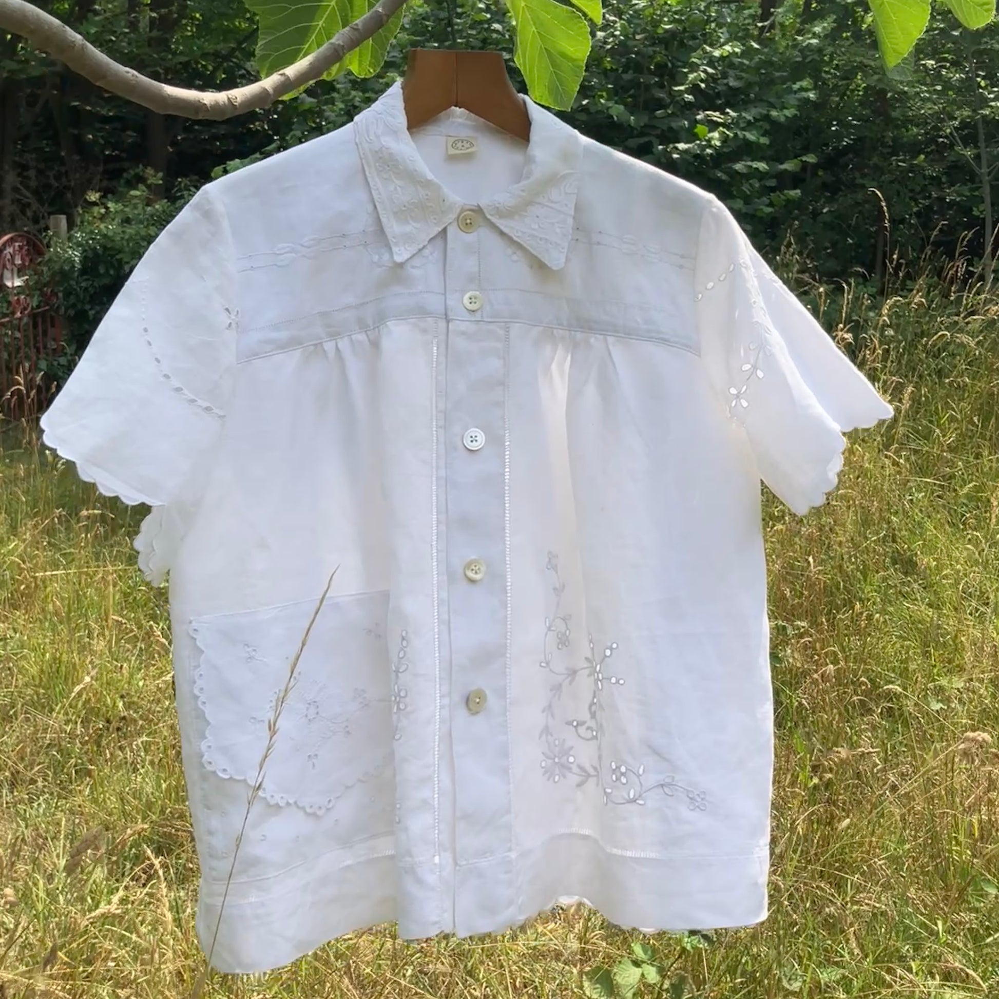 White blouse made from recycled table linen on a hanger against a natural background