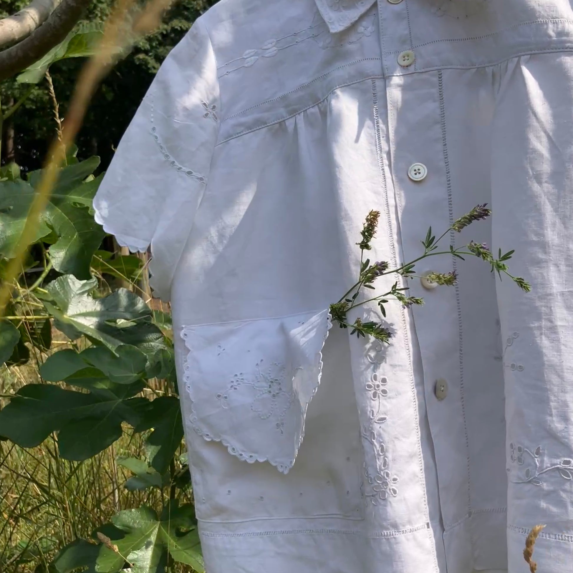Blouse made from recycled table linen on a hanger against a natural background