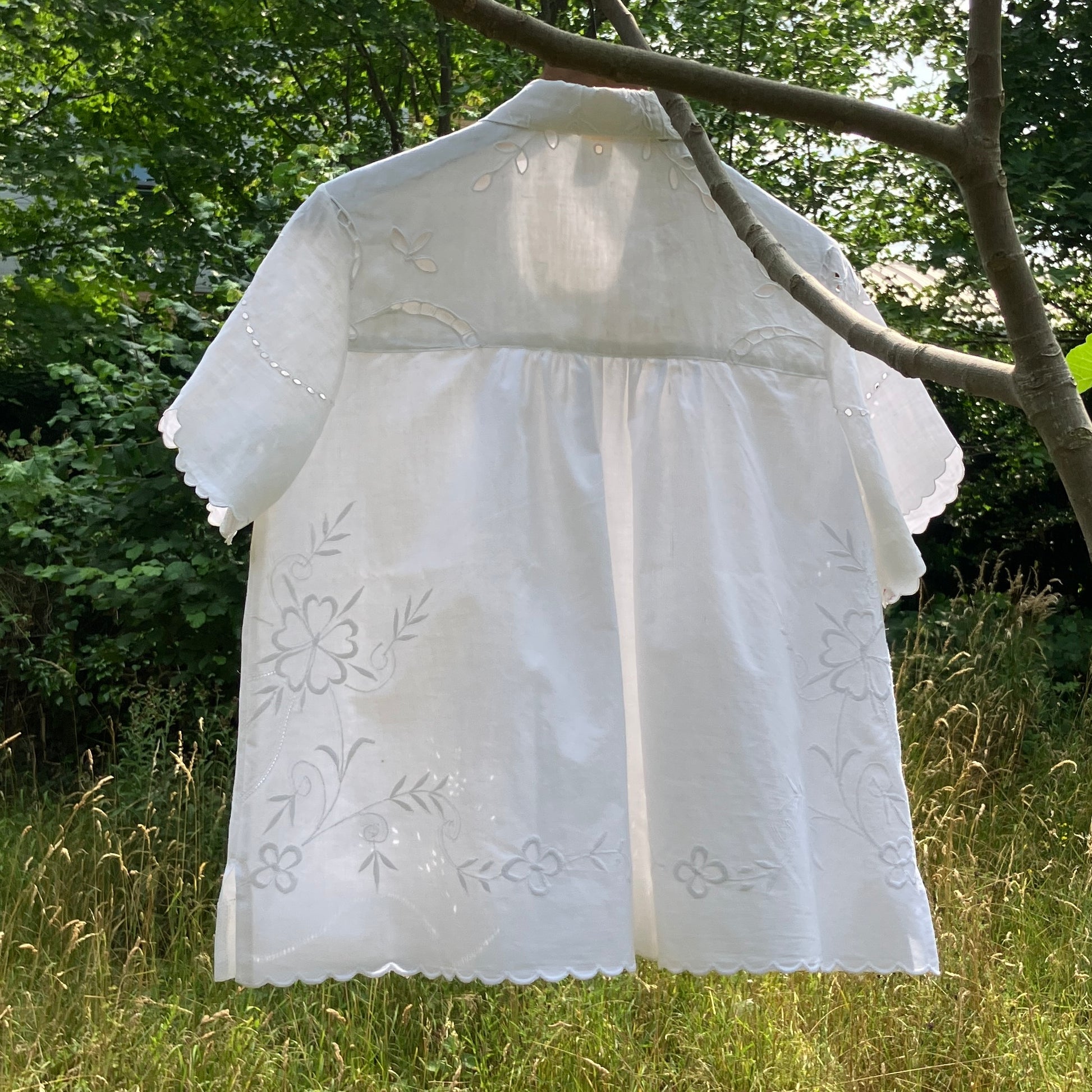 Blouse made from recycled table linen on a hanger against a natural background