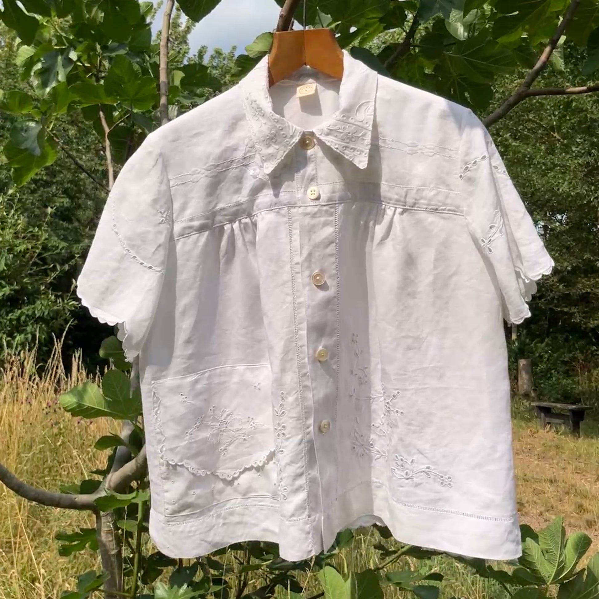 Blouse made from recycled table linen on a hanger against a natural background