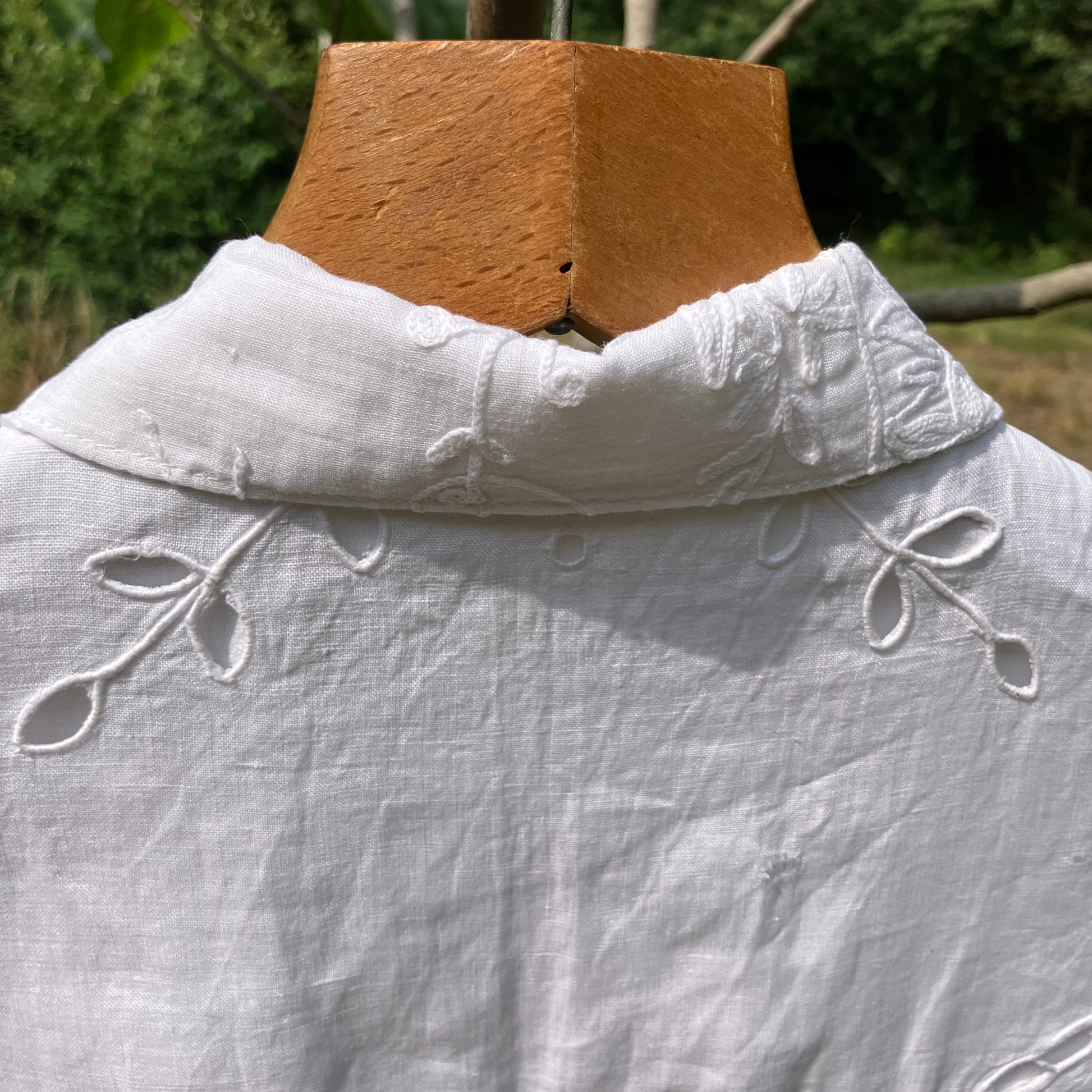 Blouse made from recycled table linen on a hanger against a natural background