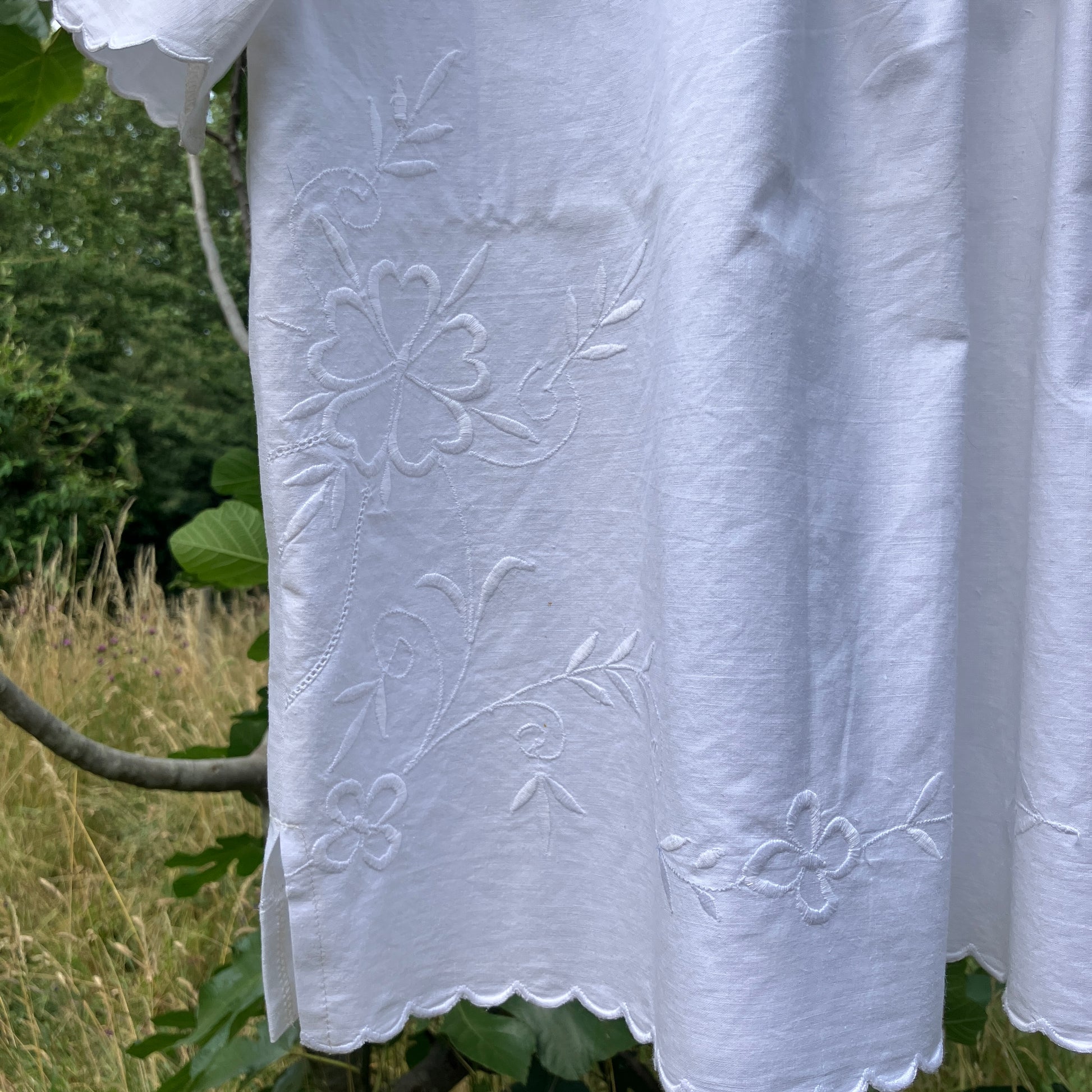 Blouse made from recycled table linen on a hanger against a natural background