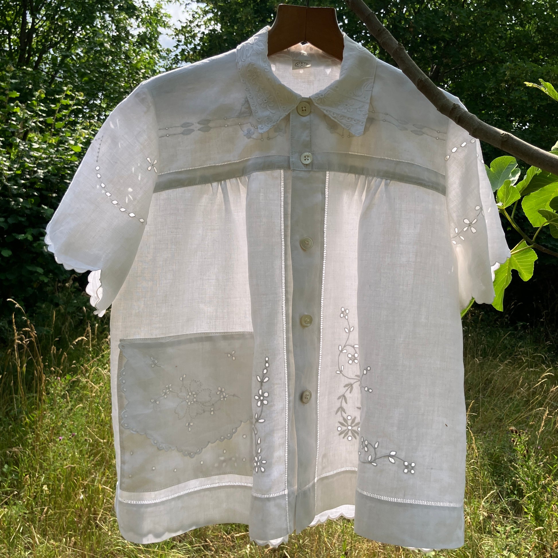 Blouse made from recycled table linen on a hanger against a natural background