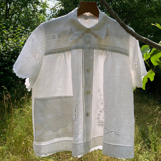 Blouse made from recycled table linen on a hanger against a natural background