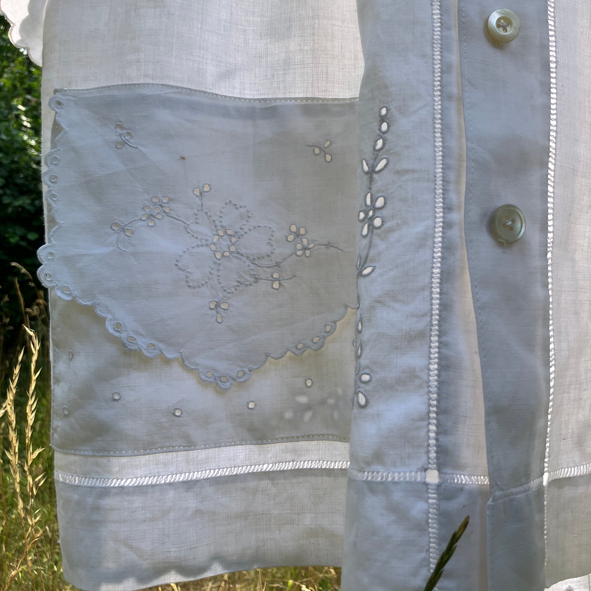 Blouse made from recycled table linen on a hanger against a natural background