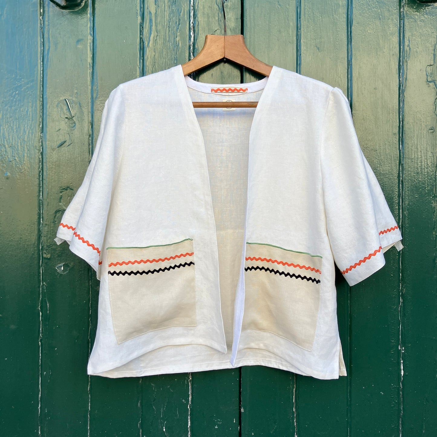 Simple linen shirt/jacket with patch pockets, ric-rac trim and a 1930s embroidered cottagecore scene appliquéd on to the back.