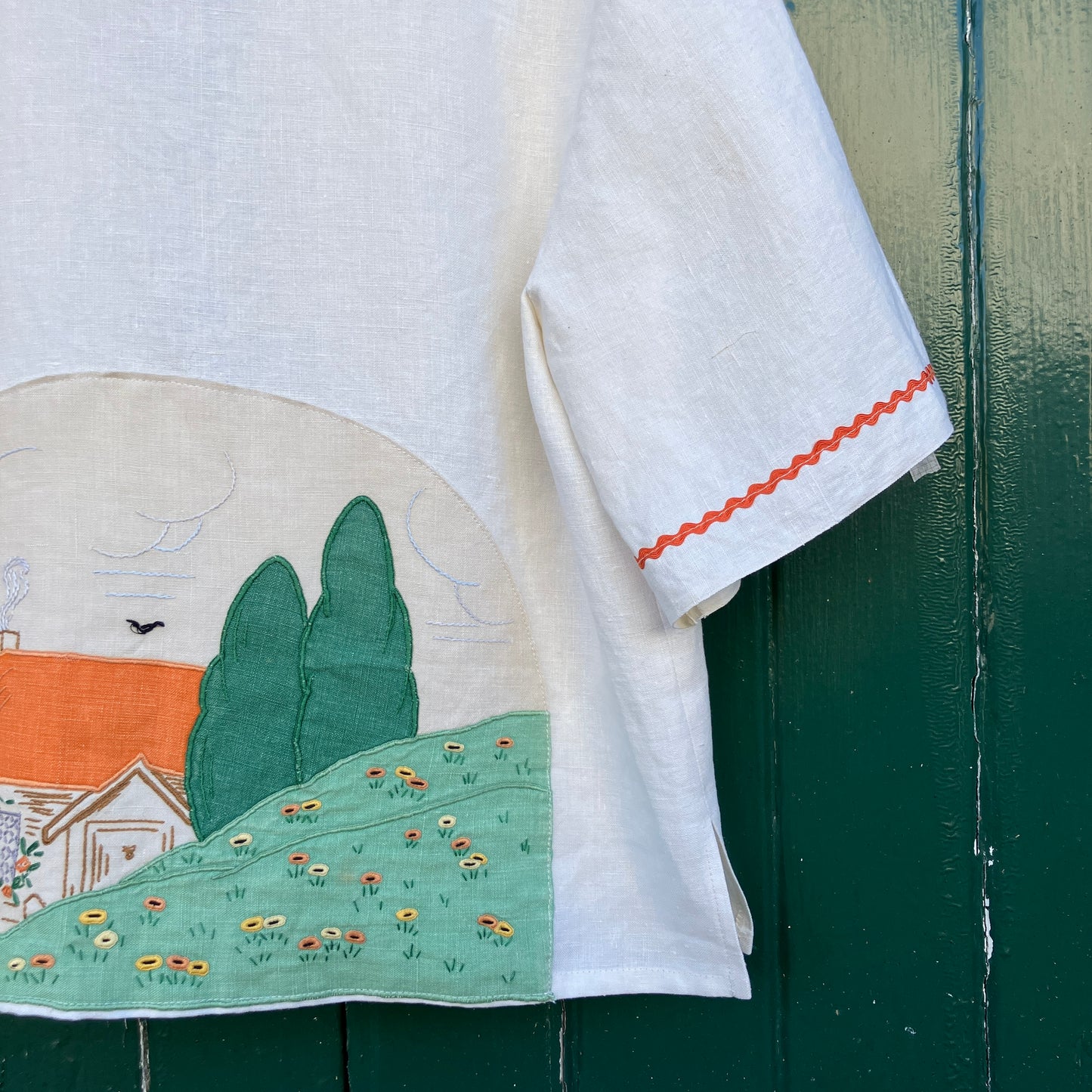 Simple linen shirt/jacket with patch pockets, ric-rac trim and a 1930s embroidered cottagecore scene appliquéd on to the back.