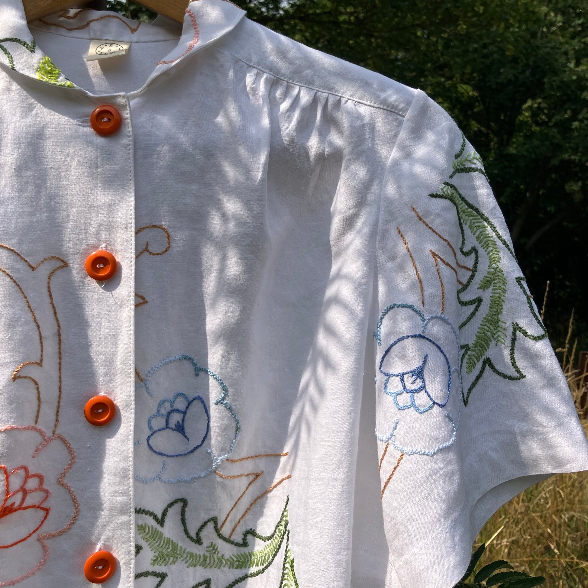 Blouse made from a recycled floral embroidered tablecloth, with cutaway collar and orange buttons