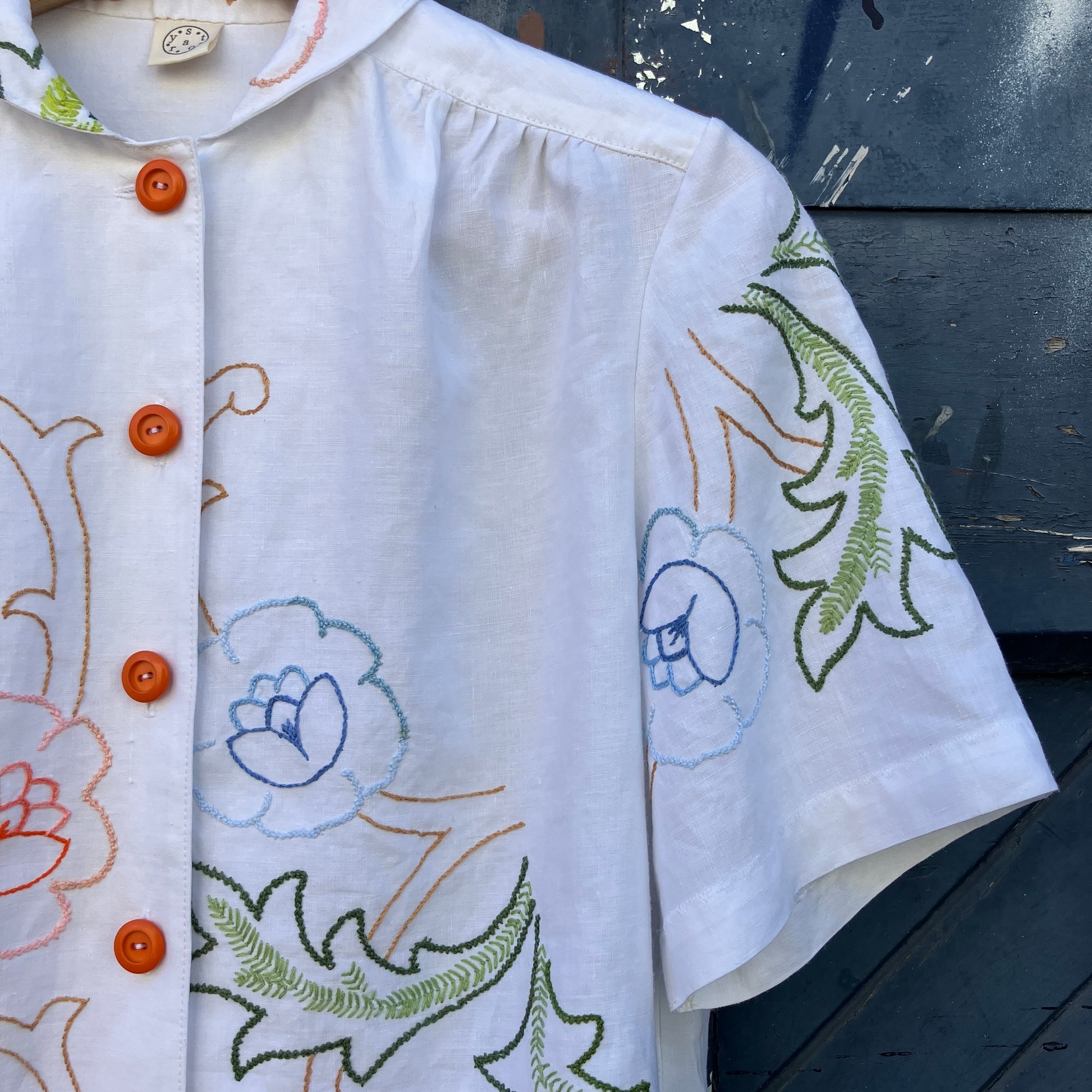 Blouse made from a recycled floral embroidered tablecloth, with cutaway collar and orange buttons