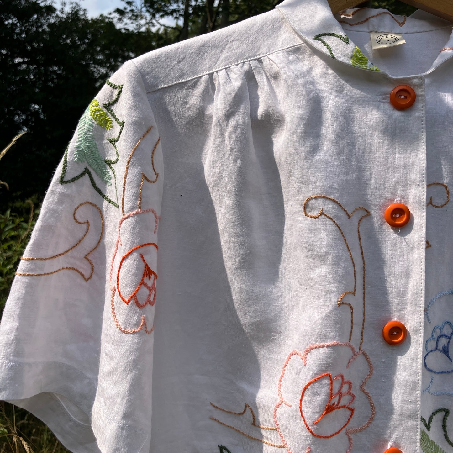 Blouse made from a recycled floral embroidered tablecloth, with cutaway collar and orange buttons