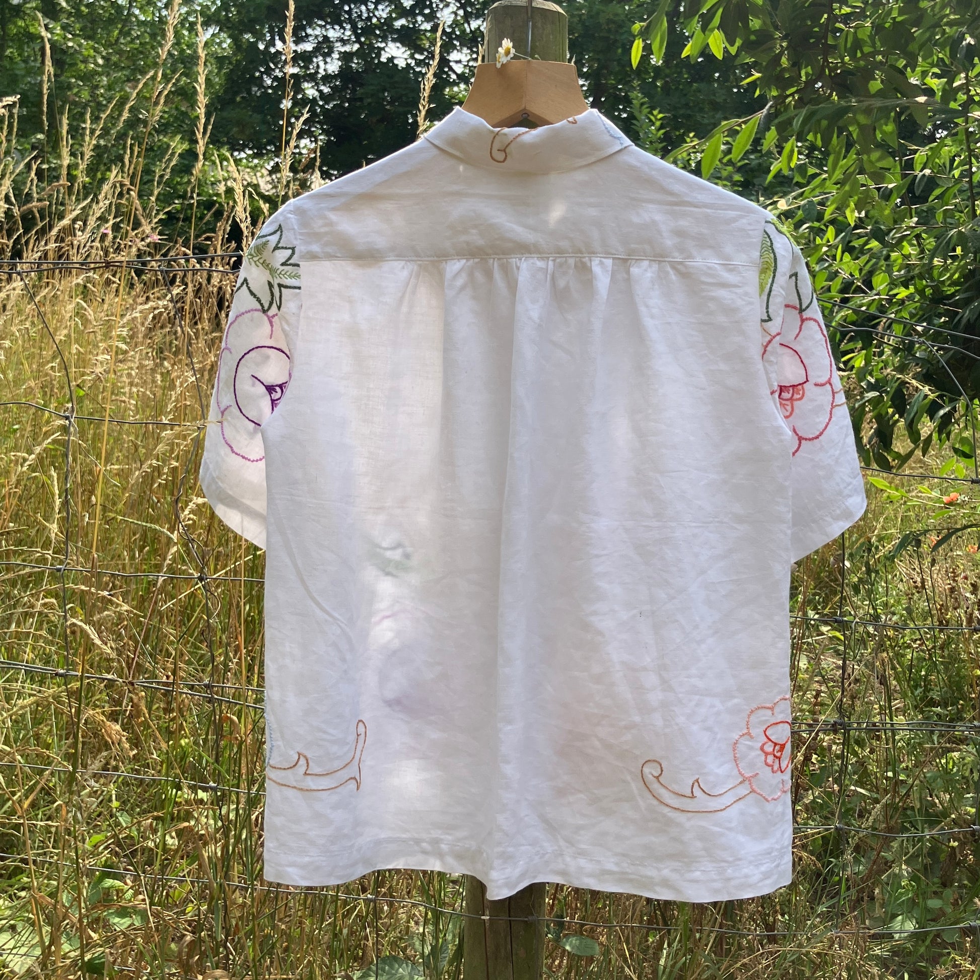 Blouse made from a recycled floral embroidered tablecloth, with cutaway collar and orange buttons