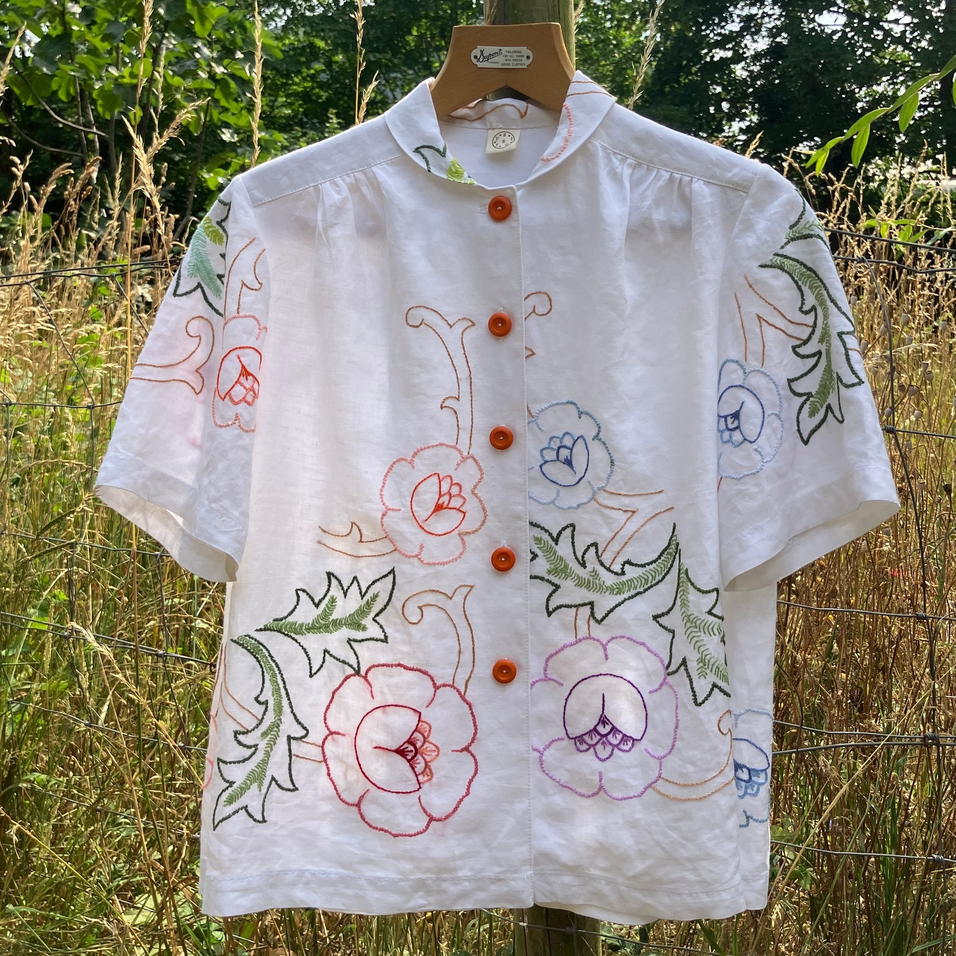 Blouse made from a recycled floral embroidered tablecloth, with cutaway collar and orange buttons