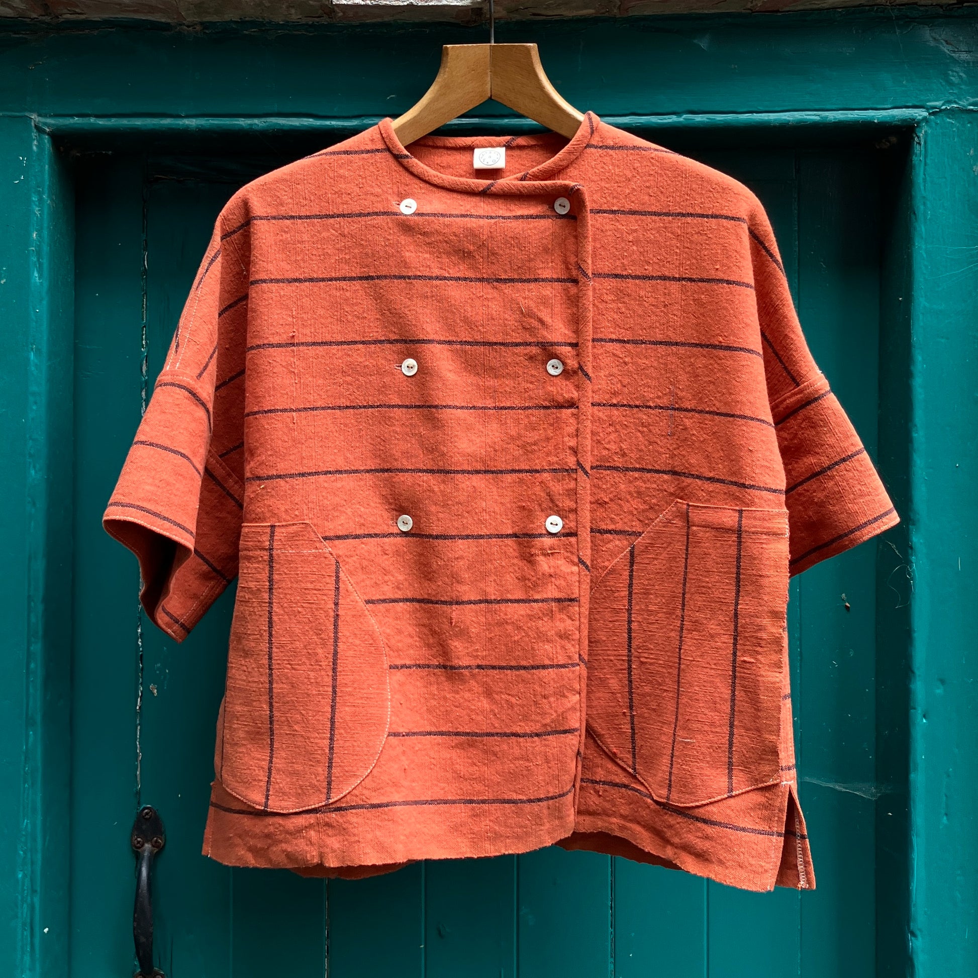 A terracotta orange boxy top with thin black stripes

