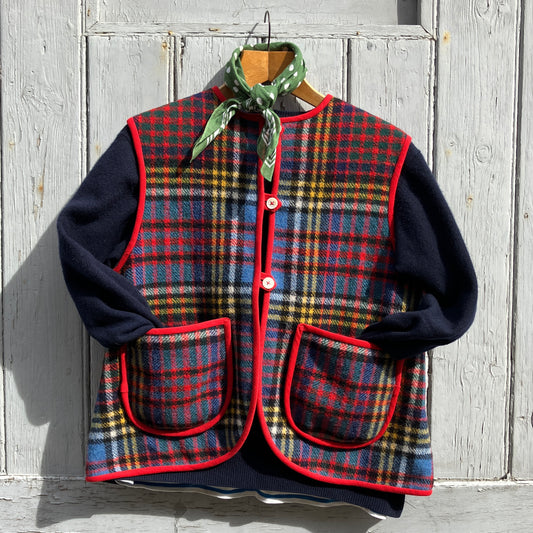 Vest/waistcoat/gilet handmade from a recycled tartan wool blanket. With red binding, two patch pockets and three shell buttons. Pictured as an outfit, with a navy jumper underneath and a green neckerchief 