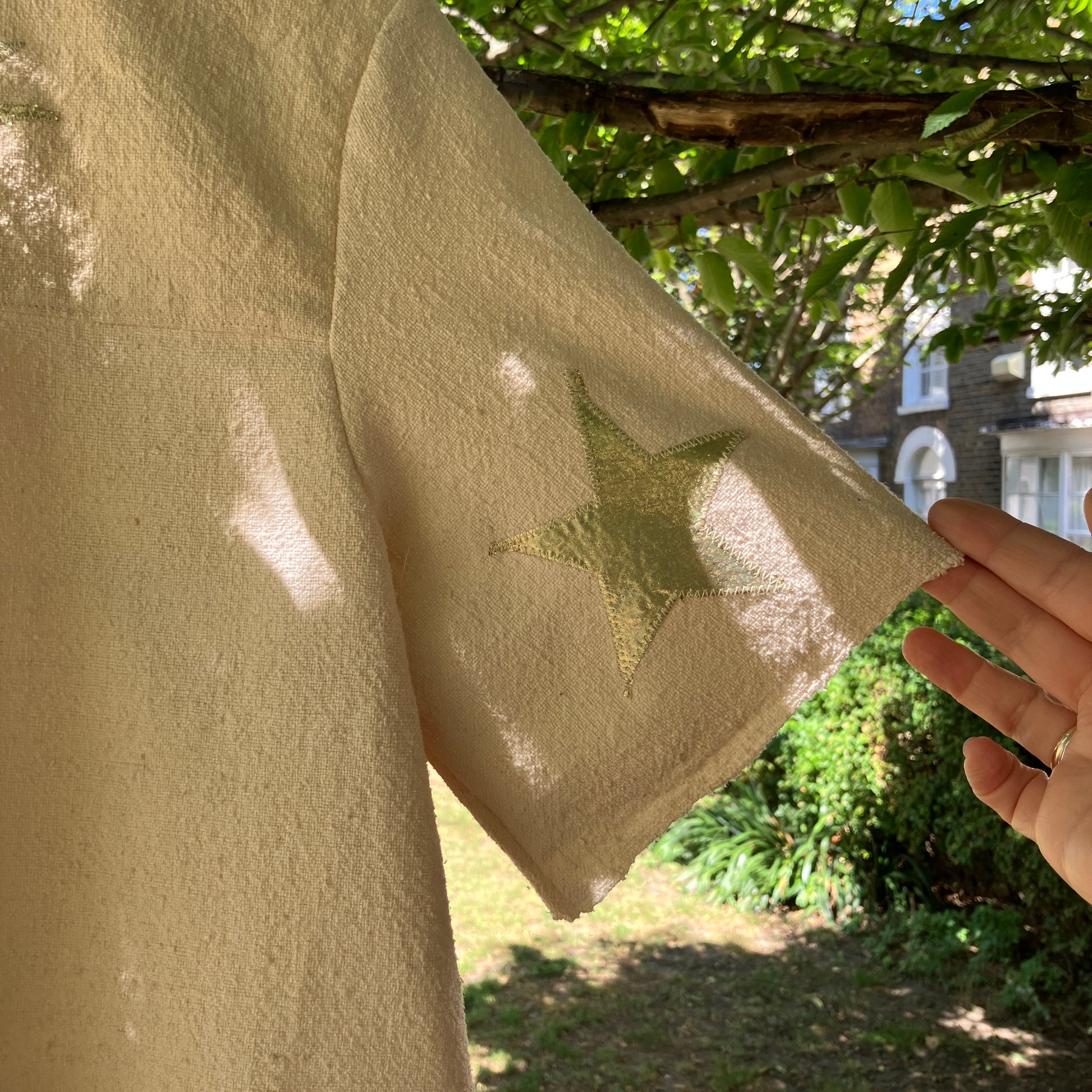 neutral-coloured raw silk smock with gold weather-themed appliqué