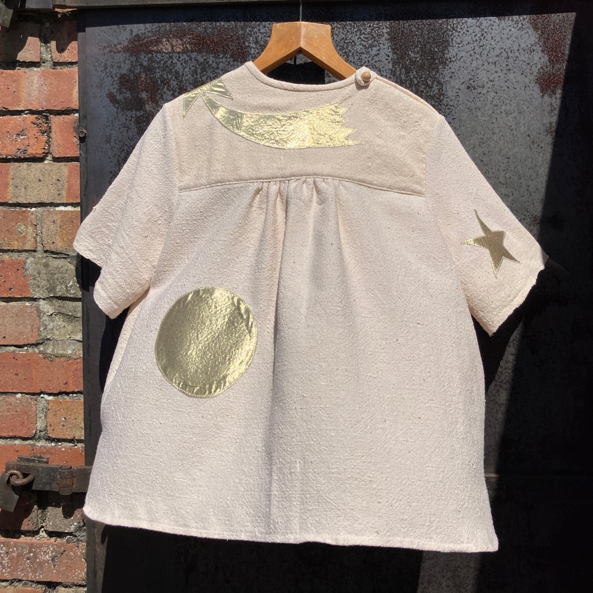 neutral-coloured raw silk smock with gold weather-themed appliqué