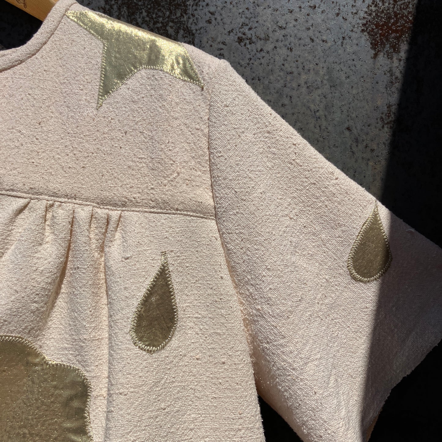 neutral-coloured raw silk smock with gold weather-themed appliqué