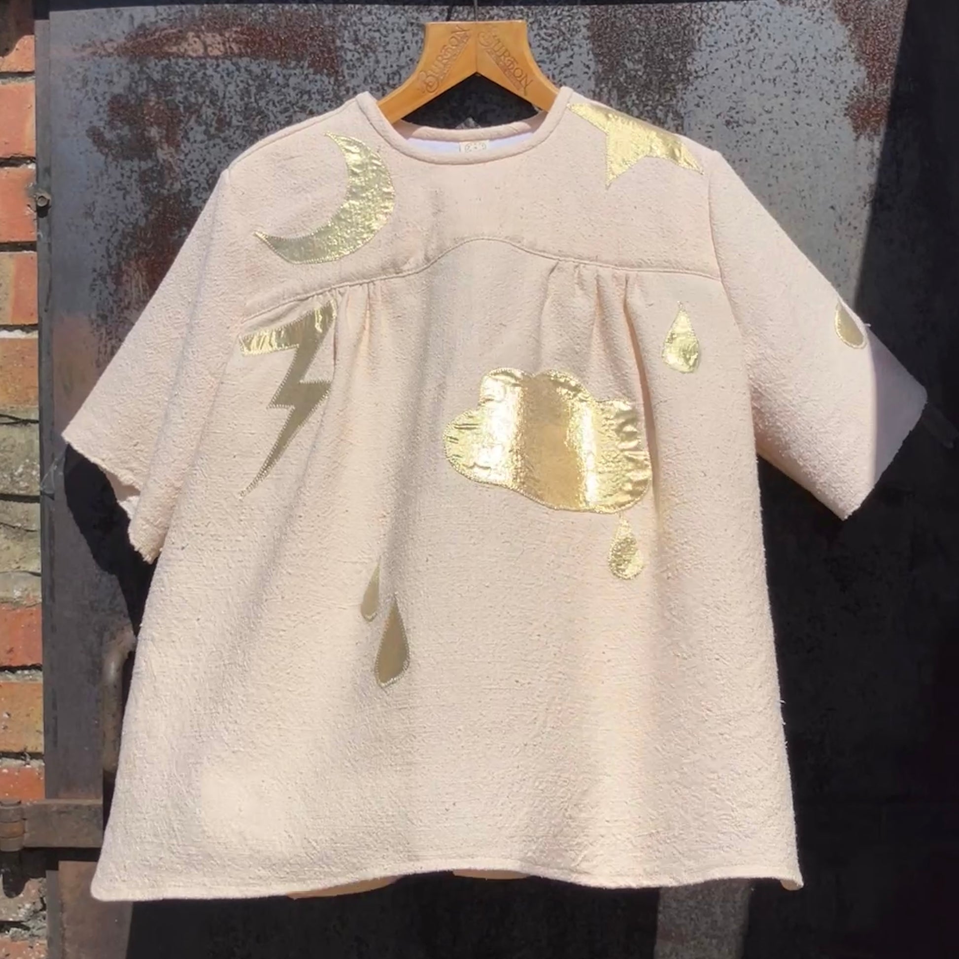 neutral-coloured raw silk smock with gold weather-themed appliqué