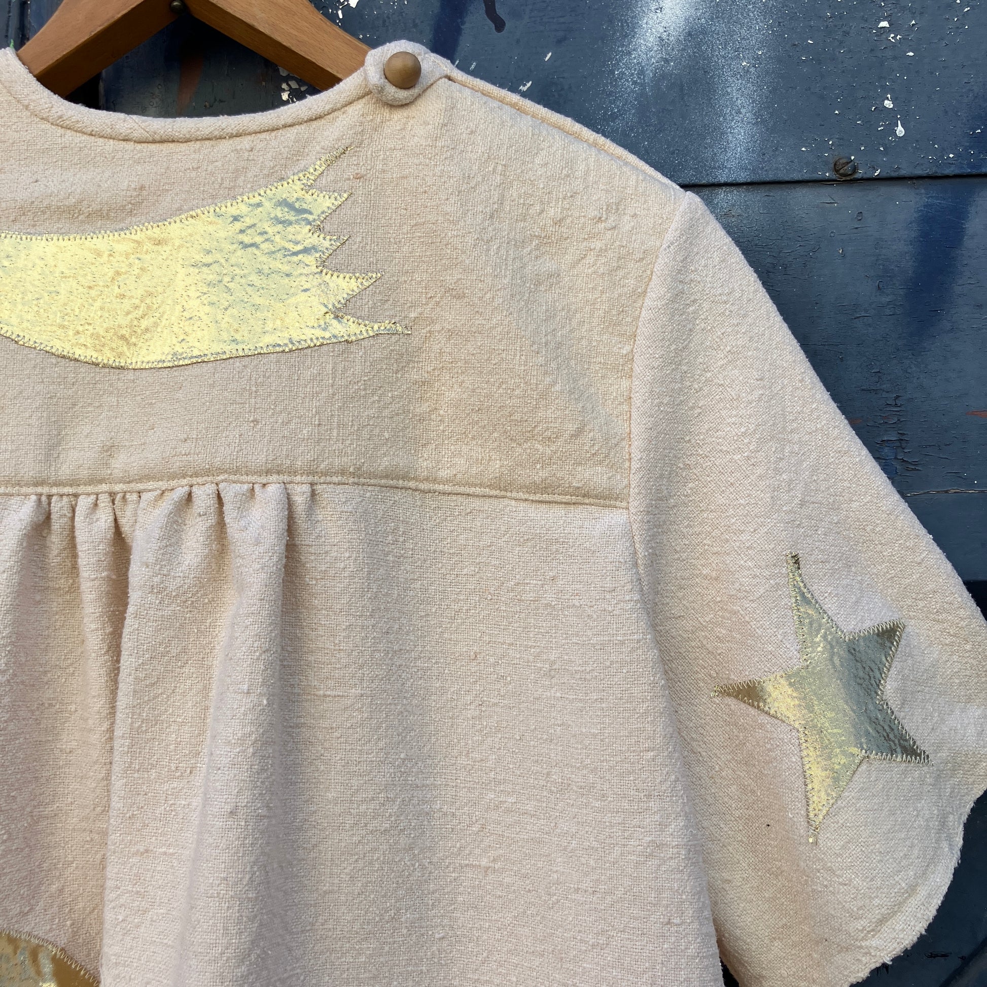 neutral-coloured raw silk smock with gold weather-themed appliqué