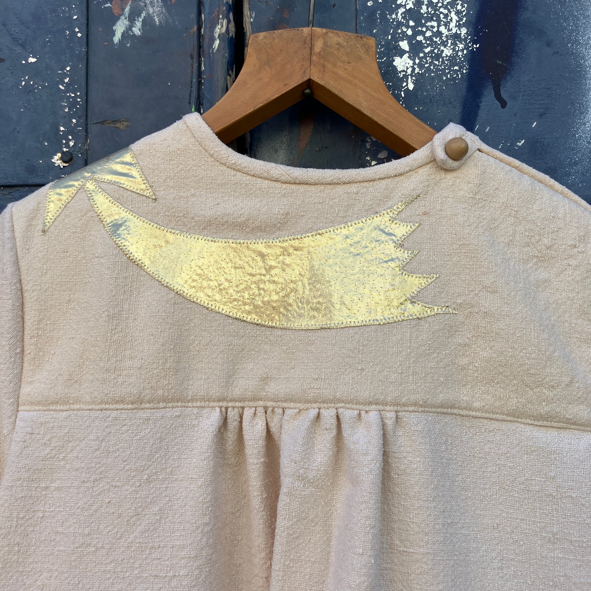 neutral-coloured raw silk smock with gold weather-themed appliqué