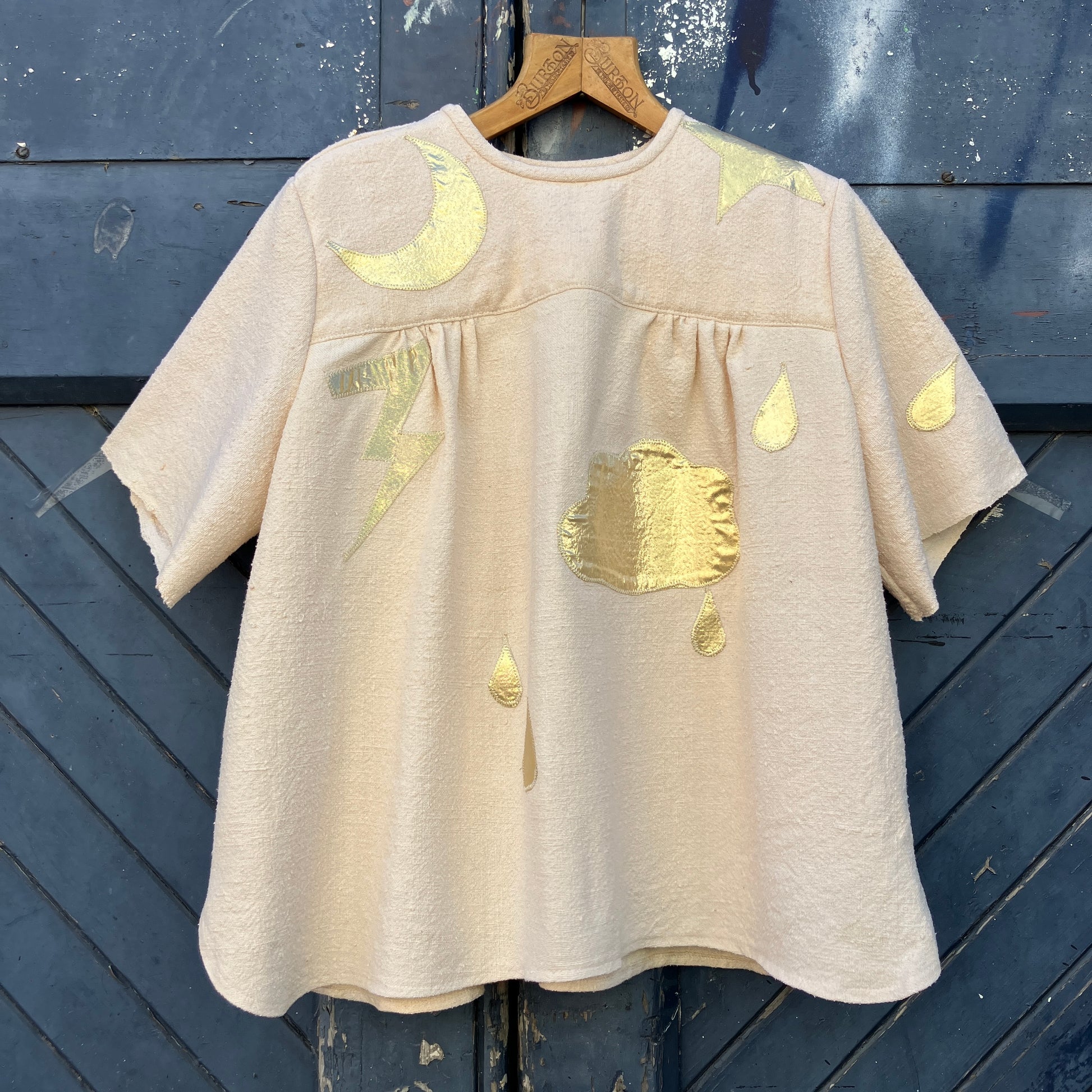 neutral-coloured raw silk smock with gold weather-themed appliqué