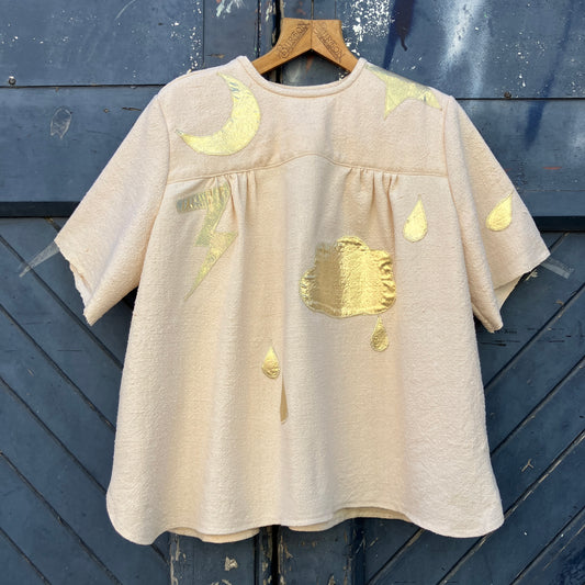 neutral-coloured raw silk smock with gold weather-themed appliqué