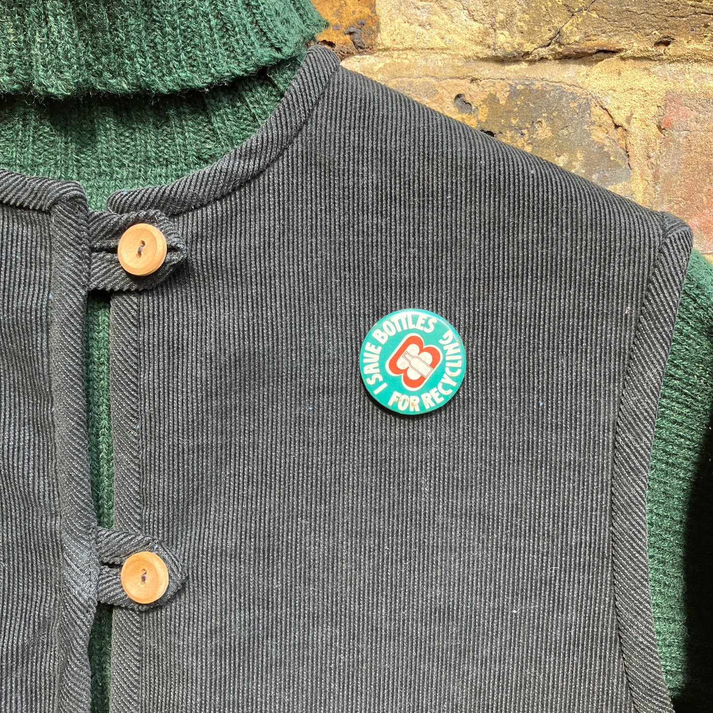 Needlecord vest/gilet/waistcoat with large hand quilted patchwork pockets in gold and silver lamé with blue binding.  Finished with wooden buttons and a hanging loop. Pictured hanging against a wall with a vintage badge pinned to it that reads 'I save bottles for recycling'