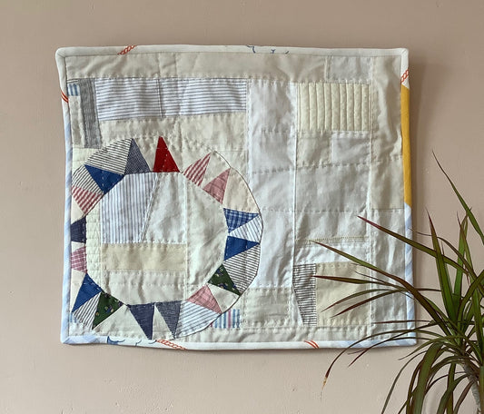 Wallhanging made from precious neutral and brightly-coloured scraps patchworked together and quilted in an improv fashion